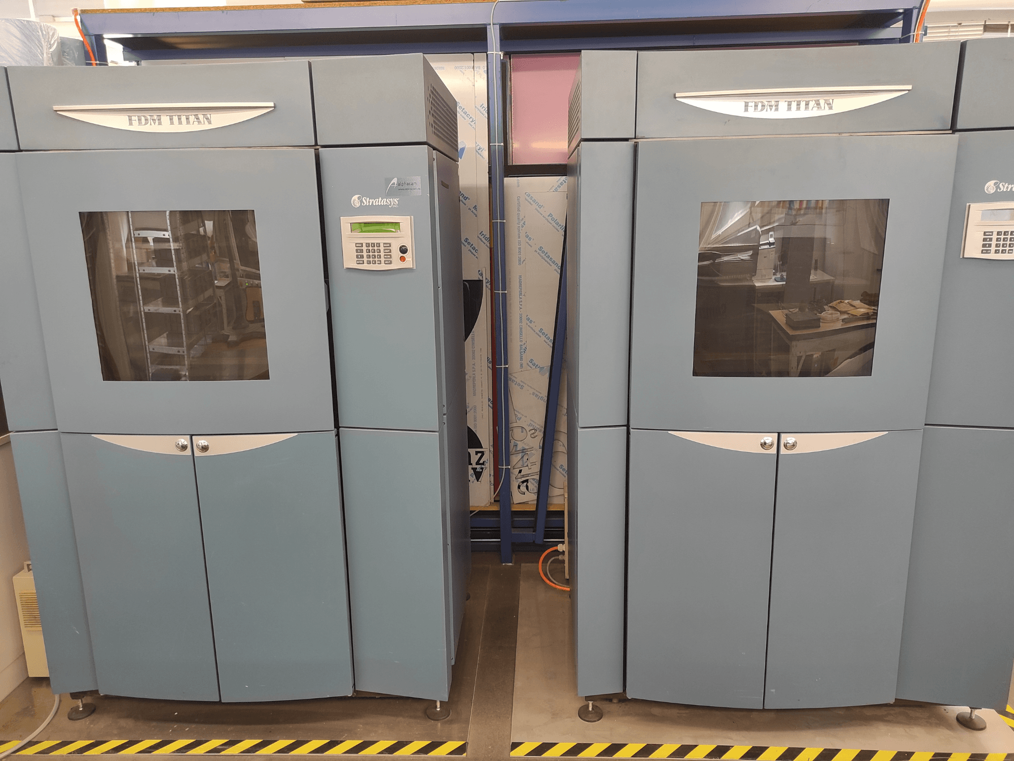 FDM TitanTI 3D-printer van Stratasys, vooraanzicht, met dubbele deuren en bedieningspaneel, geplaatst in een industriële omgeving.