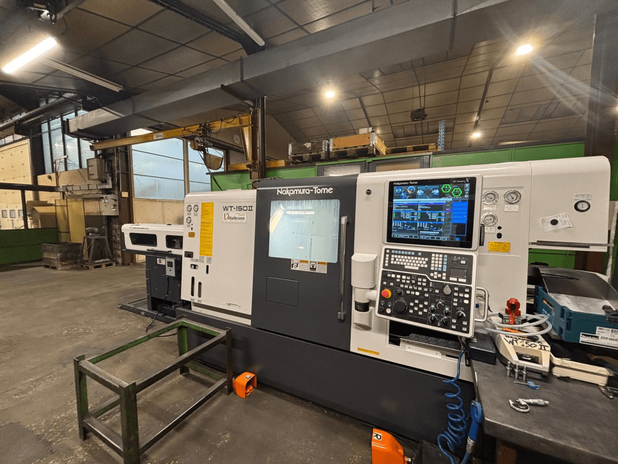 Nakamura-Tome WT-150II machine, vooraanzicht, met bedieningspaneel en gereedschappen zichtbaar op een werkbank in een werkplaats.