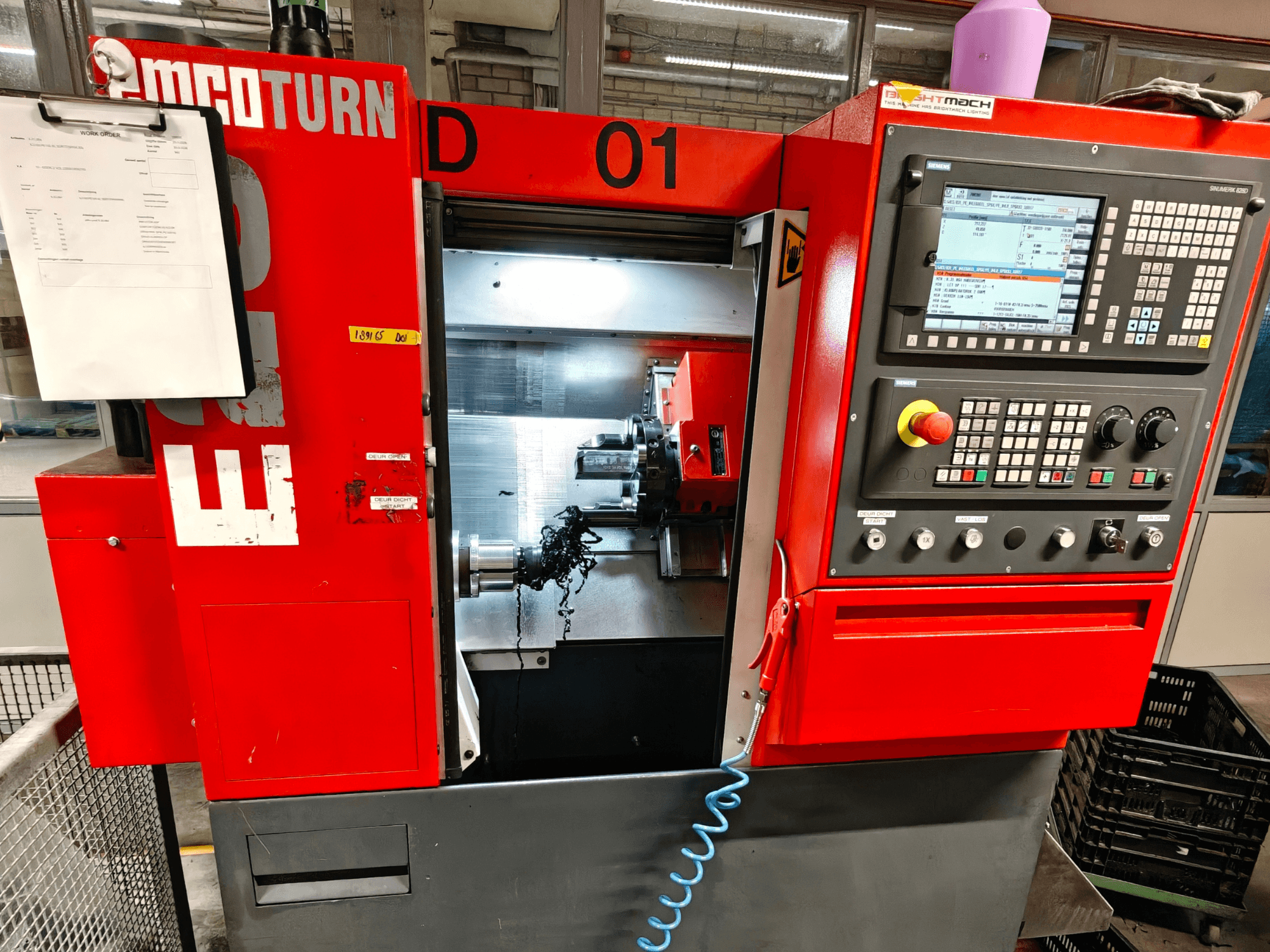 Vooraanzicht van EMCO TURN E25 horizontale draaimachine, met bedieningselementen, gereedschaphouder en werkgebied met spanen.