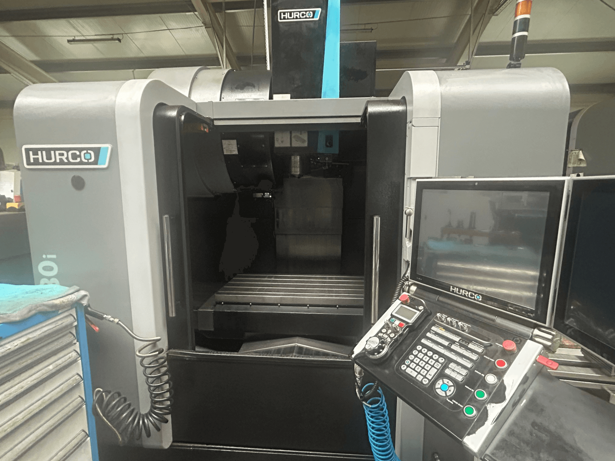 Vooraanzicht Hurco VM30i CNC machine, met bedieningspaneel met knoppen, display en gereedschapopslag.