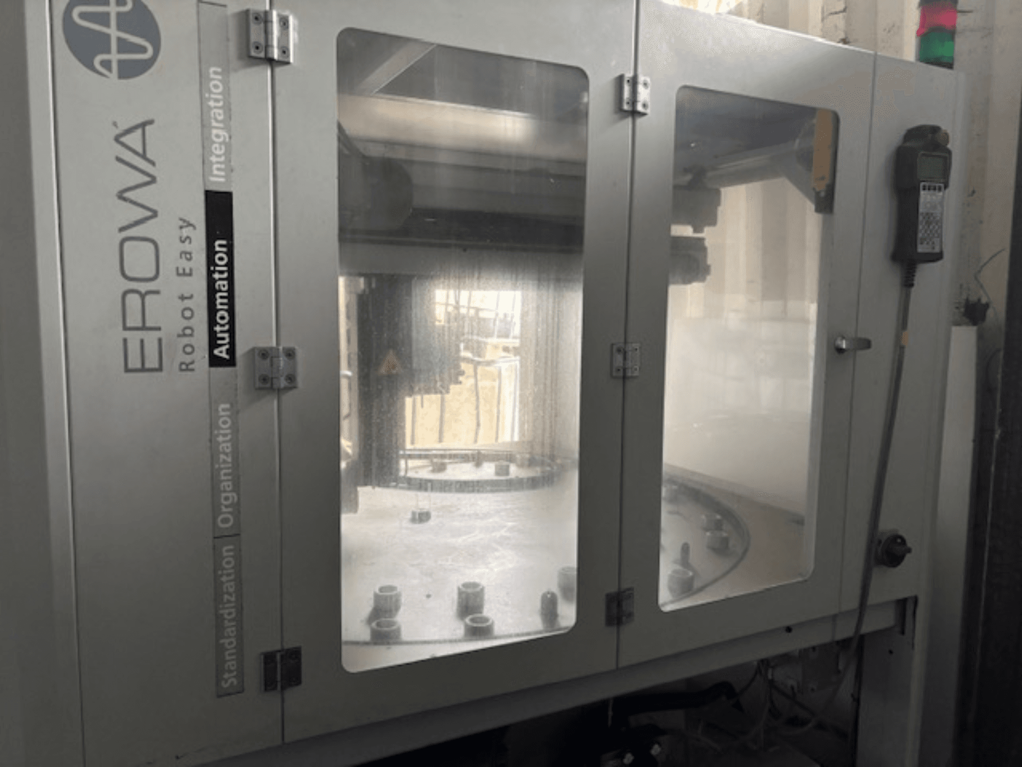 Vooraanzicht van EROWA Robot Easy Automation; voorzien van heldere deuren, zichtbare automatiseringscomponenten en bedieningspaneel.