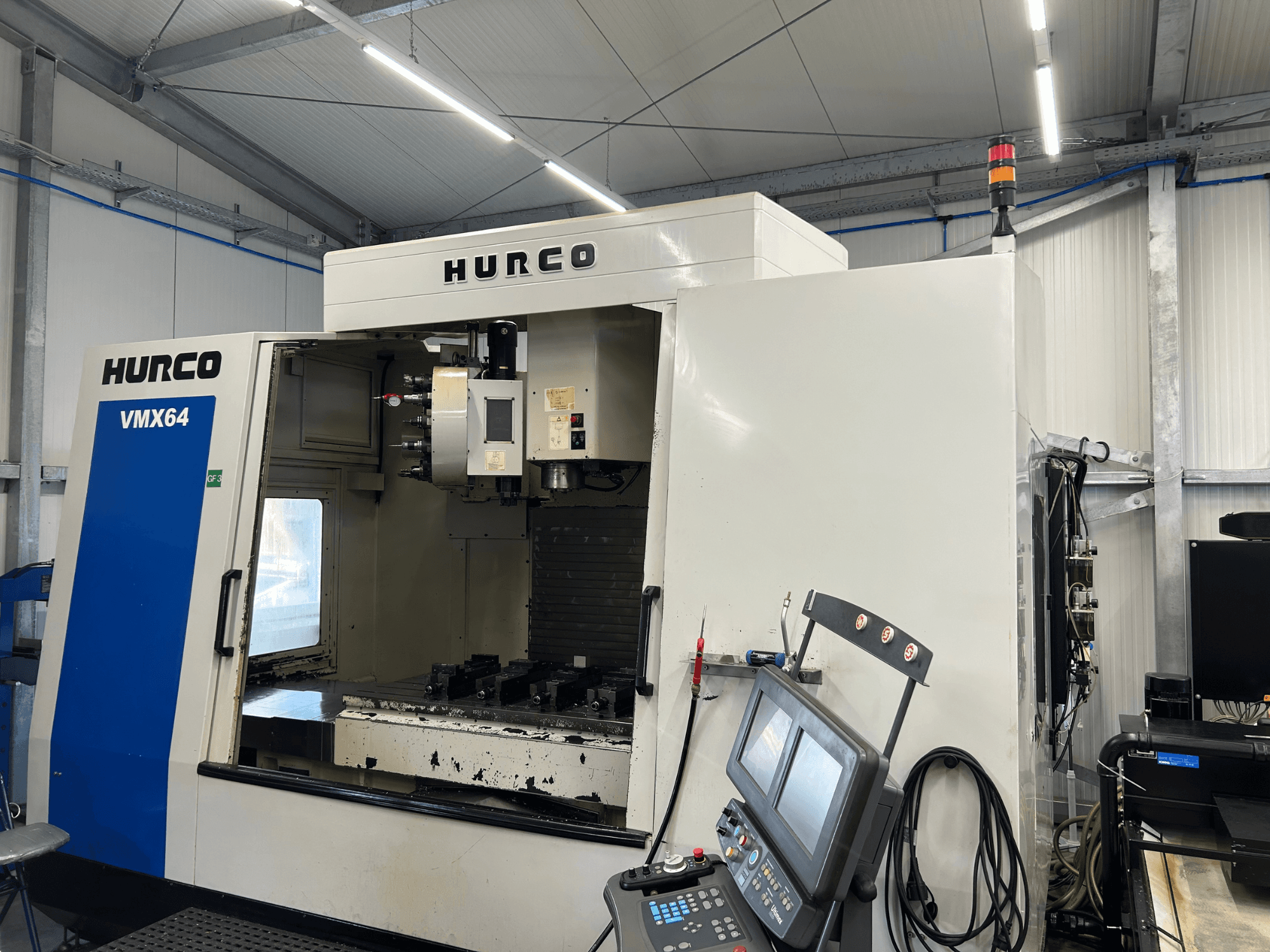 Hurco VMX 64 verticaal bewerkingscentrum, vooraanzicht, met het bedieningspaneel en de open werkruimte met gereedschappen.