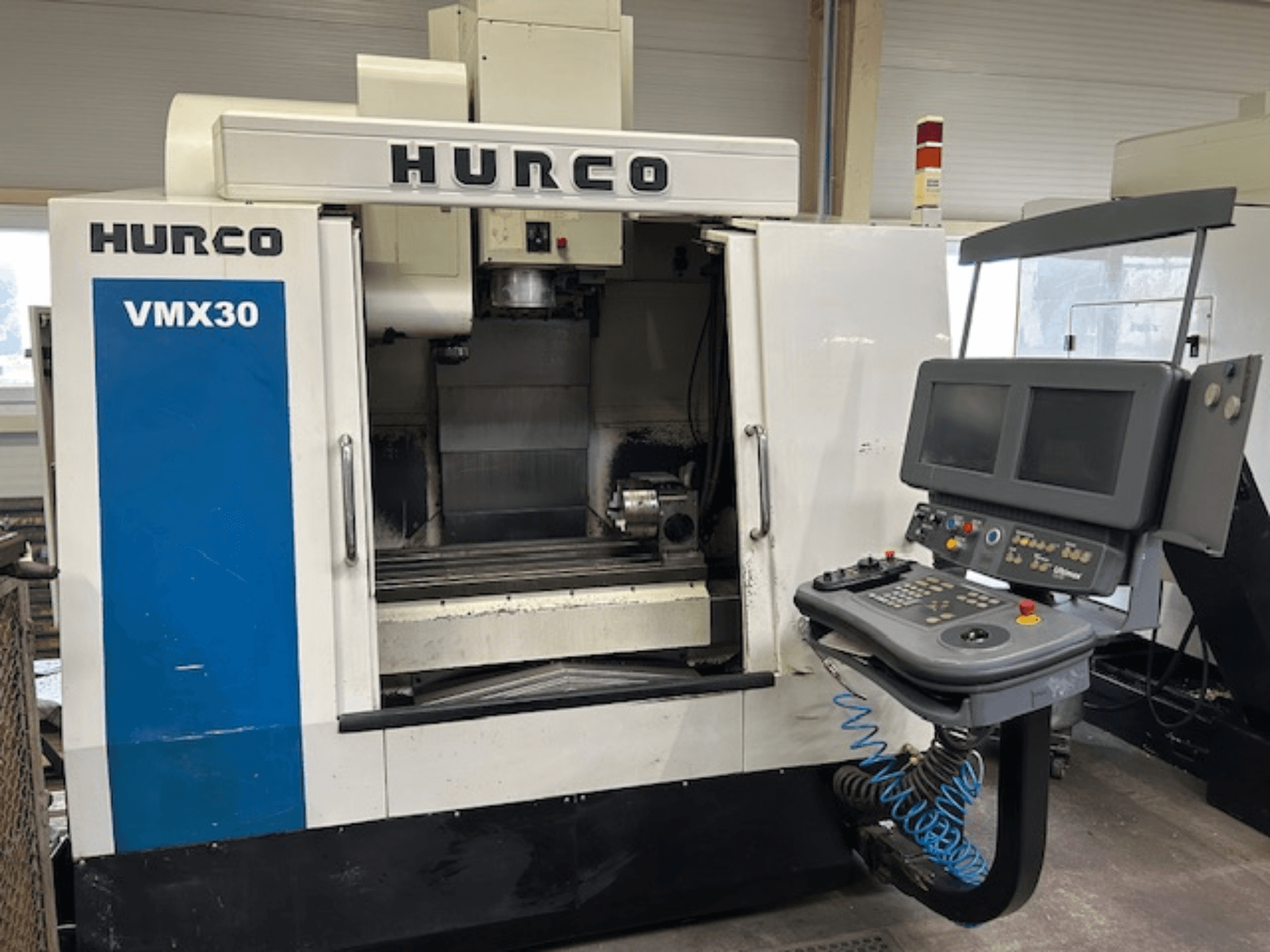 Hurco VMX30 CNC freesmachine in een werkplaats, vooraanzicht; voorzien van bedieningspaneel met dubbele schermen en bedieningsknoppen.