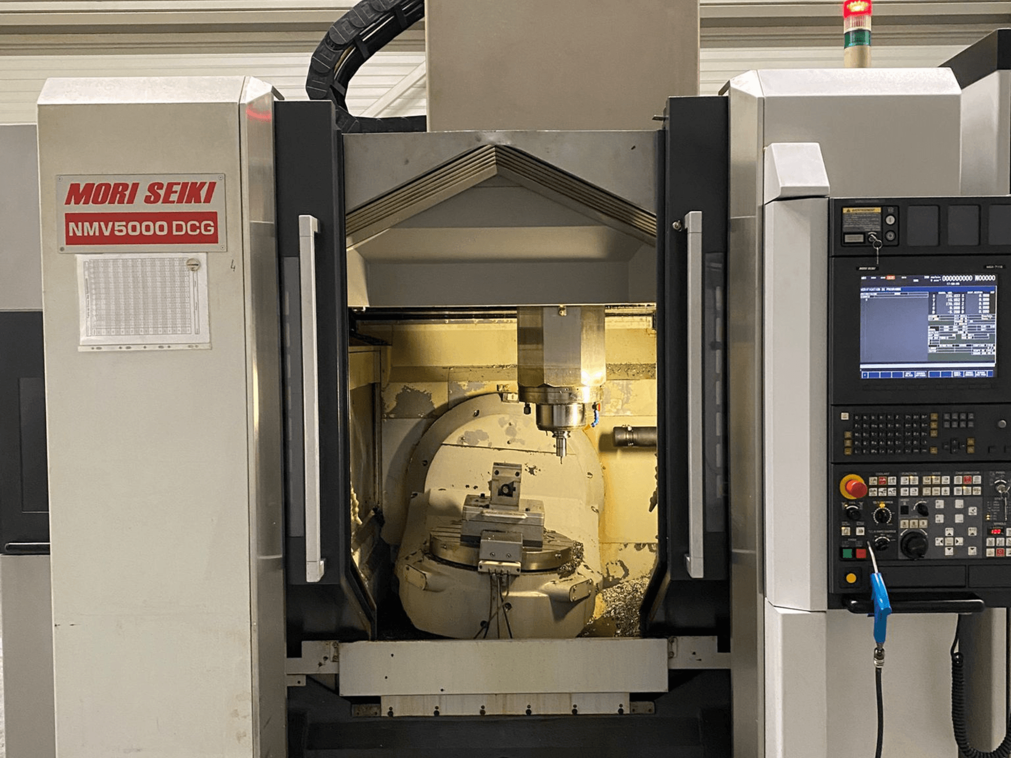 MORI SEIKI NMV 5000DCG universeel bewerkingscentrum, vooraanzicht met bedieningspaneel en binnenruimte.