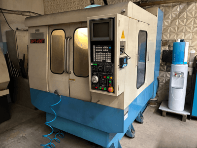 SPT-V30T CNC machine in blauw en wit, vooraanzicht met bedieningspaneel, deuren en luchtslang. Perfect voor precisiebewerking.