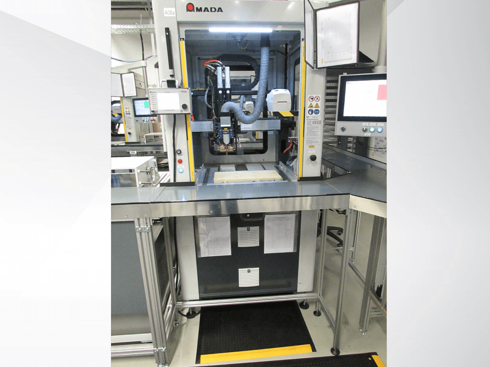 Vooraanzicht van de AMADA Jupiter System-automatiseringsmachine met bedieningspaneel, monitor en een overzichtelijke werkruimte voor de bediening.