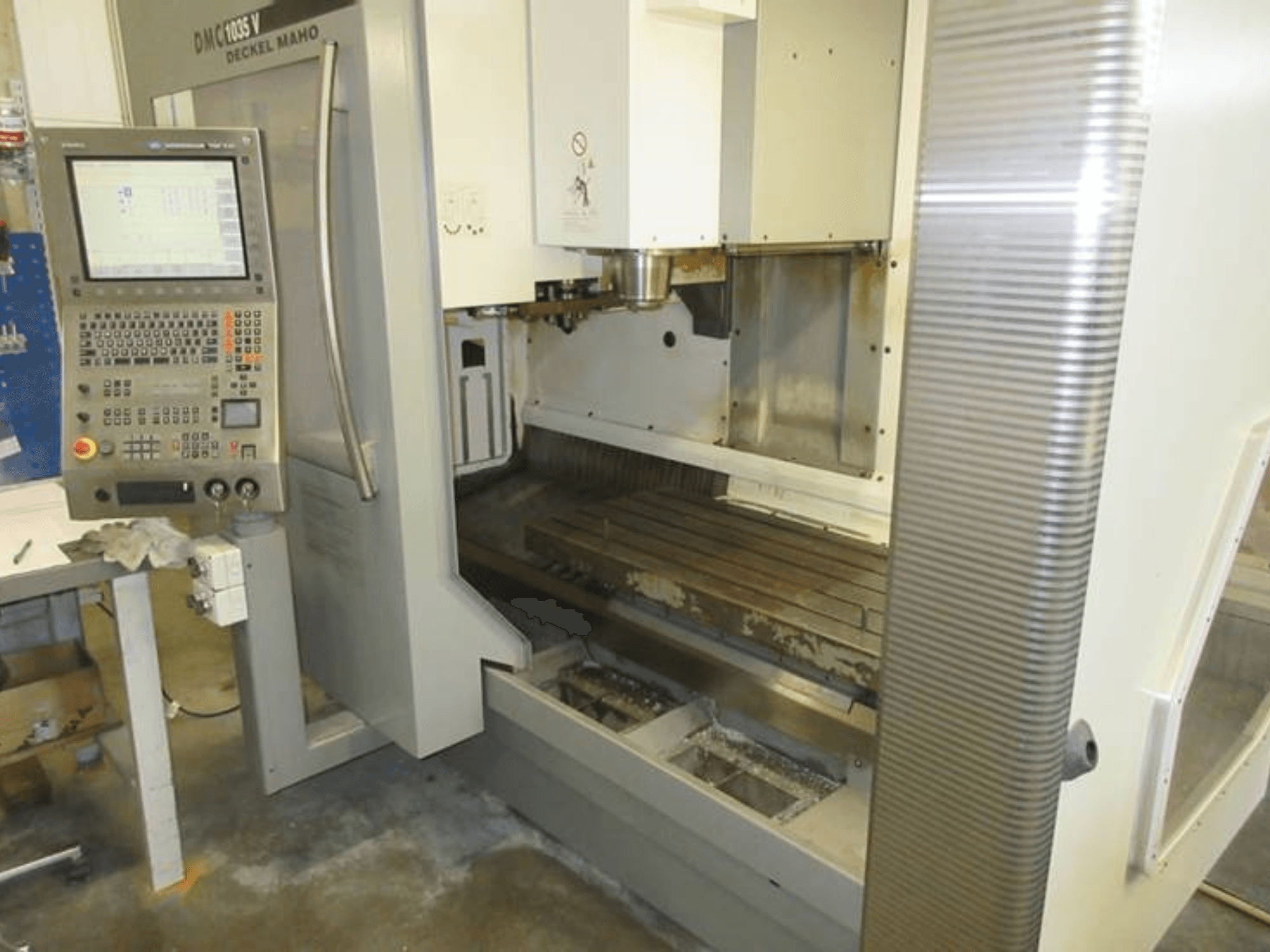 Vooraanzicht van het verticale bewerkingscentrum DECKEL MAHO DMC 1035 V met bedieningspaneel, zichtbare werktafel en spilgebied.