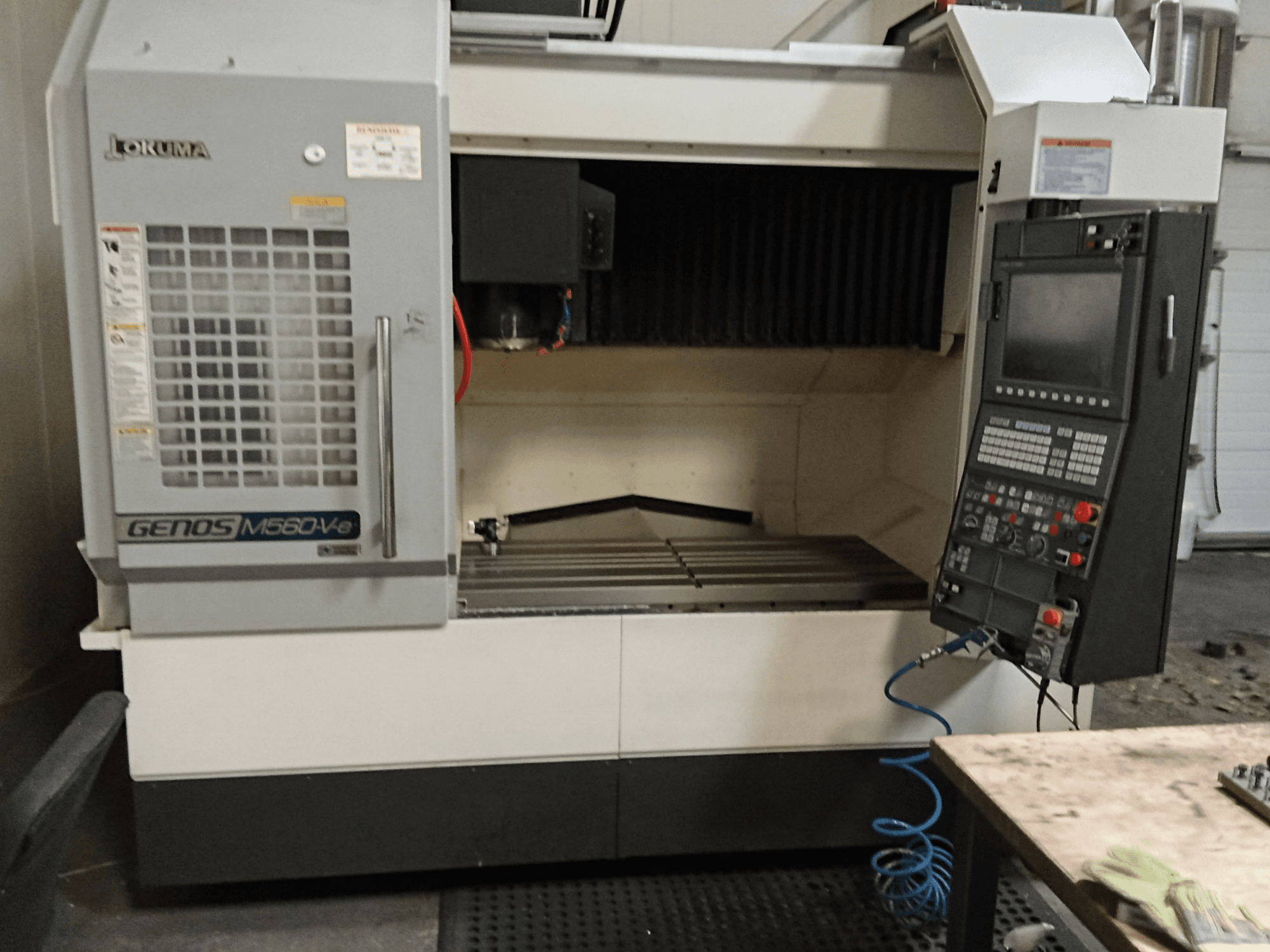 Okuma GENOS M560-V, vooraanzicht van een verticaal bewerkingscentrum met bedieningspaneel, CNC-interface en zichtbaar snijgedeelte.
