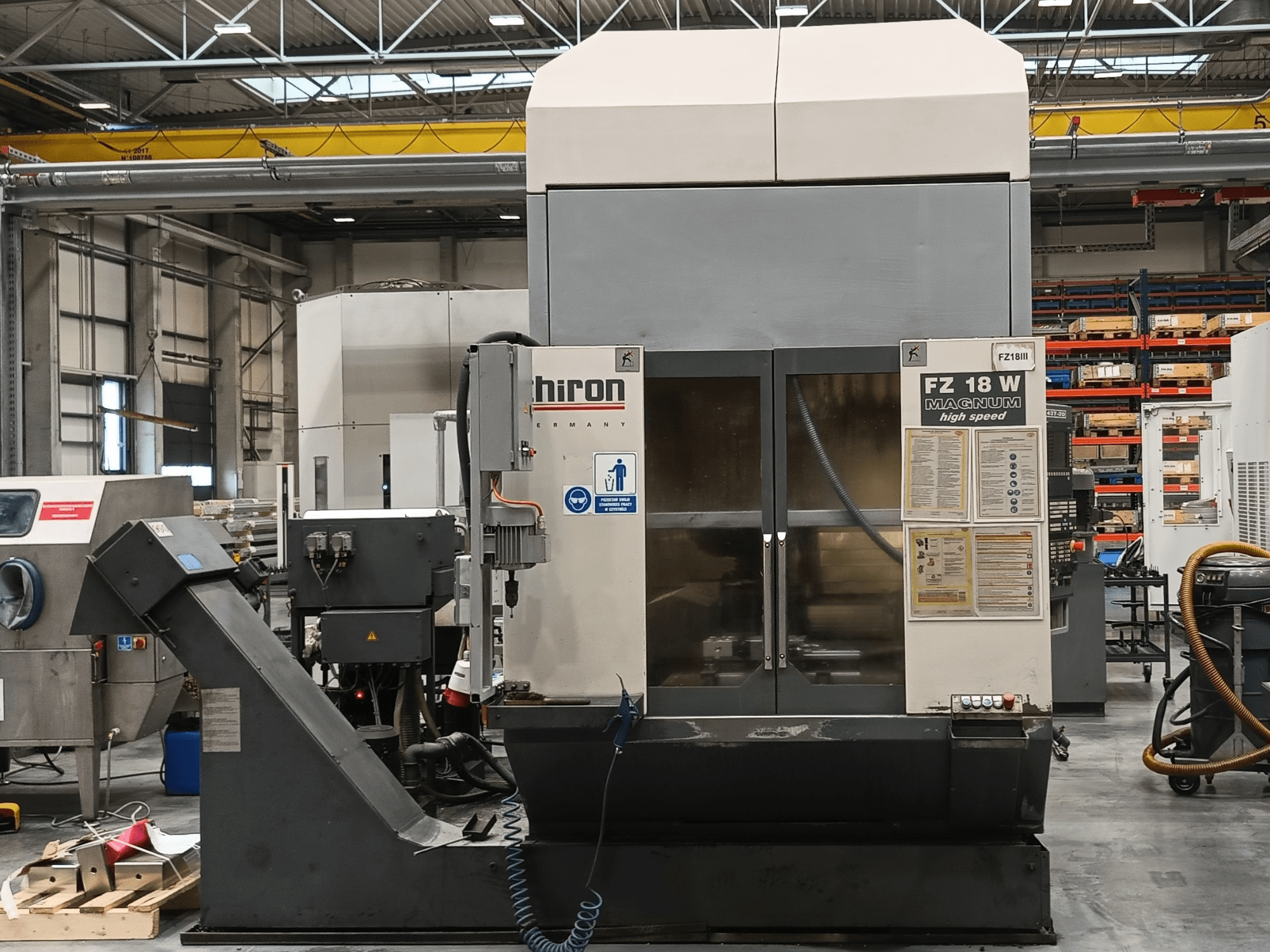 Hiron FZ 18 W Magnum CNC machine, vooraanzicht, met bedieningselementen, veiligheidslabels en industriële instelling met gereedschappen.