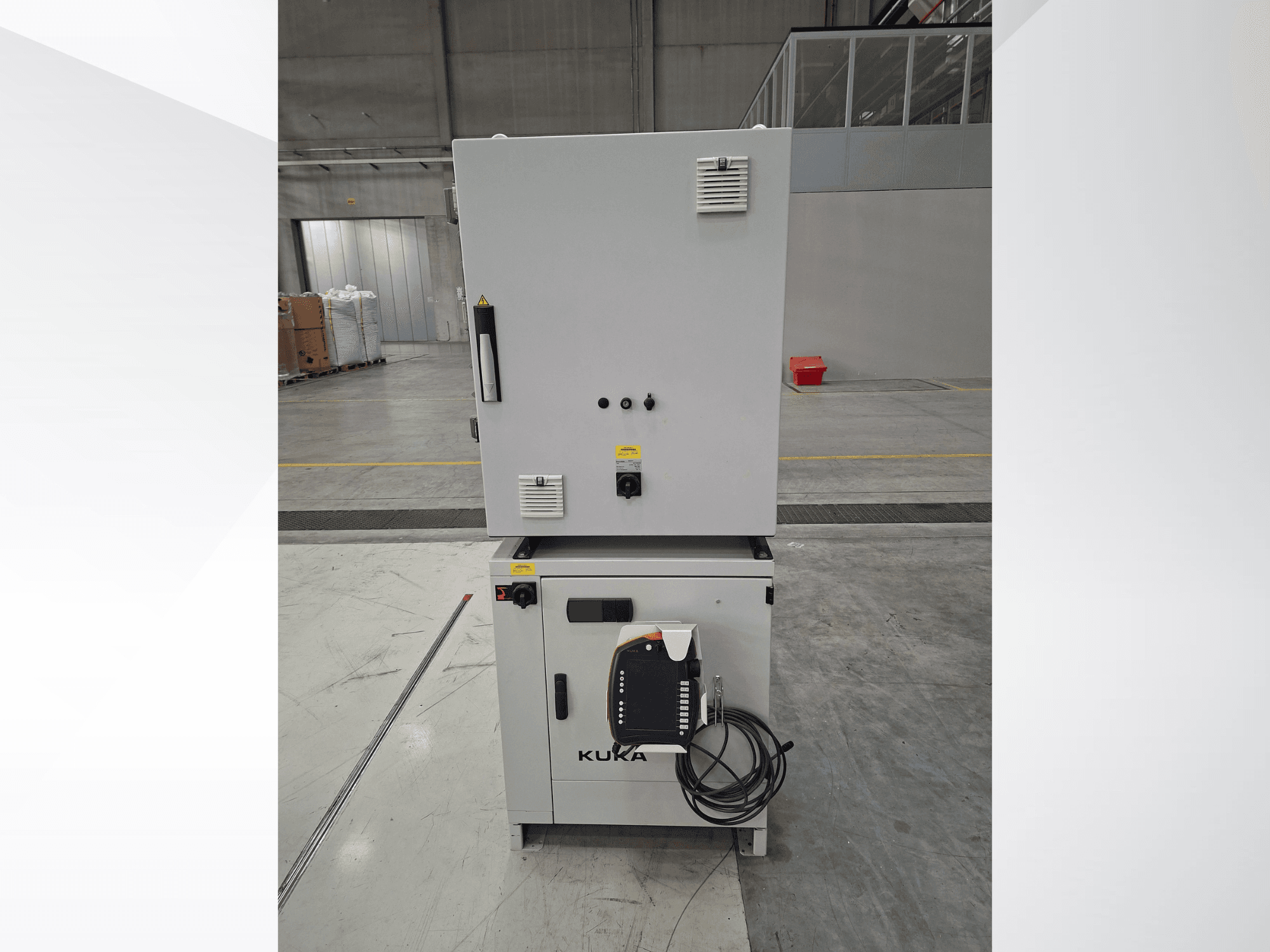 KUKA KR 90 R2700 PRO C4 FLR-robotarmbesturing, vooraanzicht met bedieningspaneel en veiligheidslabels in een ruim magazijn.