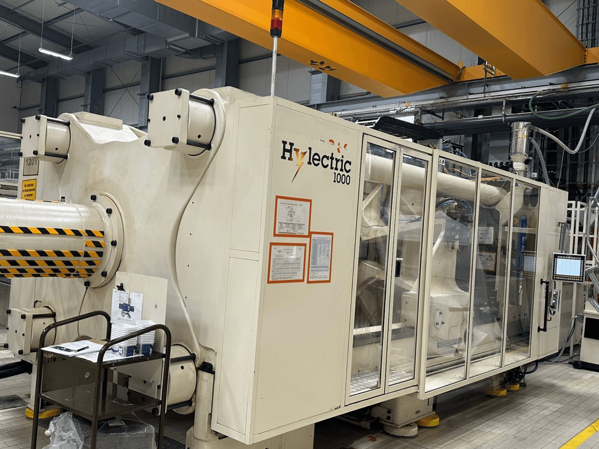 Husky Hylelectric H1000 RS95/80 elektrische spuitgietmachine, zijaanzicht met zichtbaar bedieningspaneel en veiligheidsvoorzieningen.