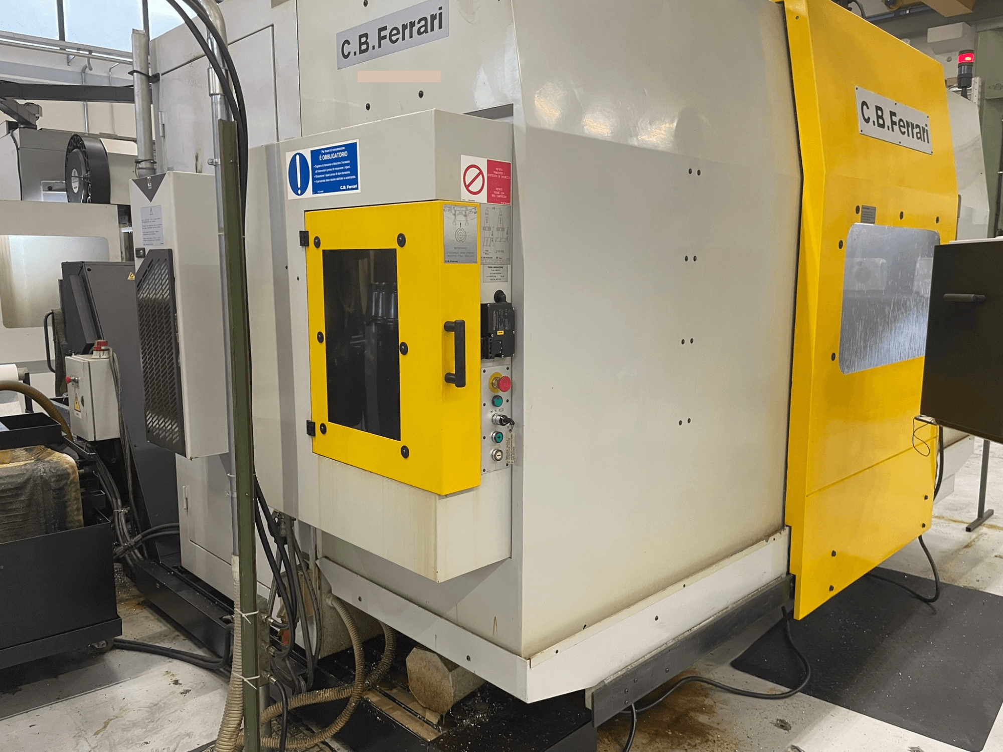 Industriële machine van C.B. Ferrari, vooraanzicht; gele deur, bedieningspaneel en zichtbare bewerkingsonderdelen.
