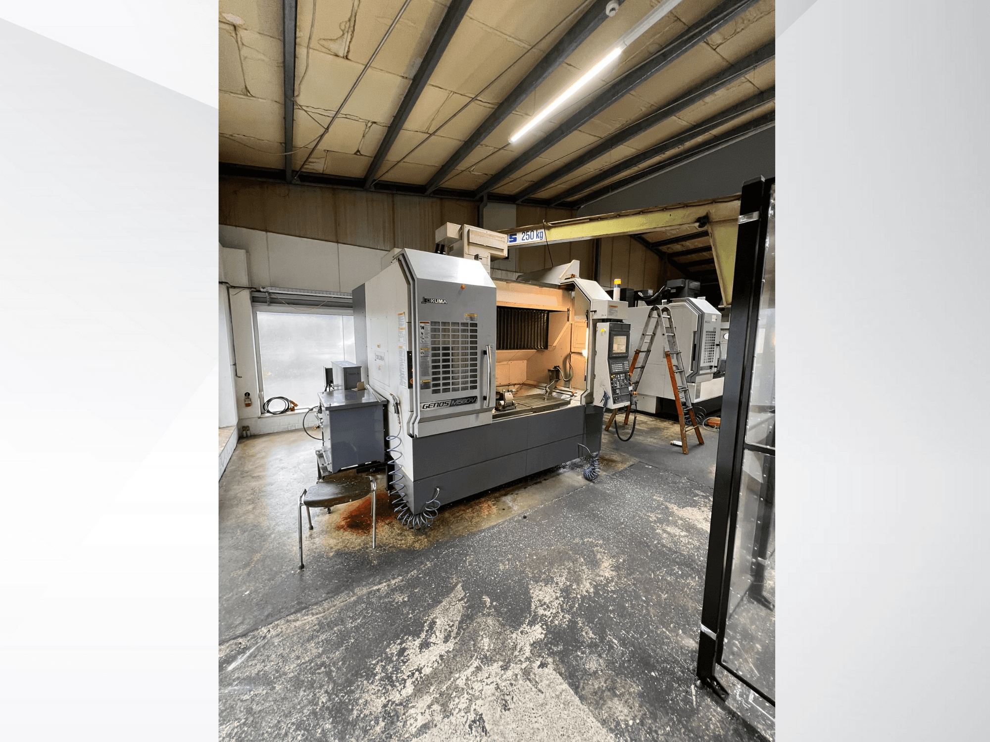 GRETOS 750 CNC machine in een werkplaats, vooraanzicht, met bedieningspaneel en werkgebied met gereedschappen, zichtbare ladder op de achtergrond.