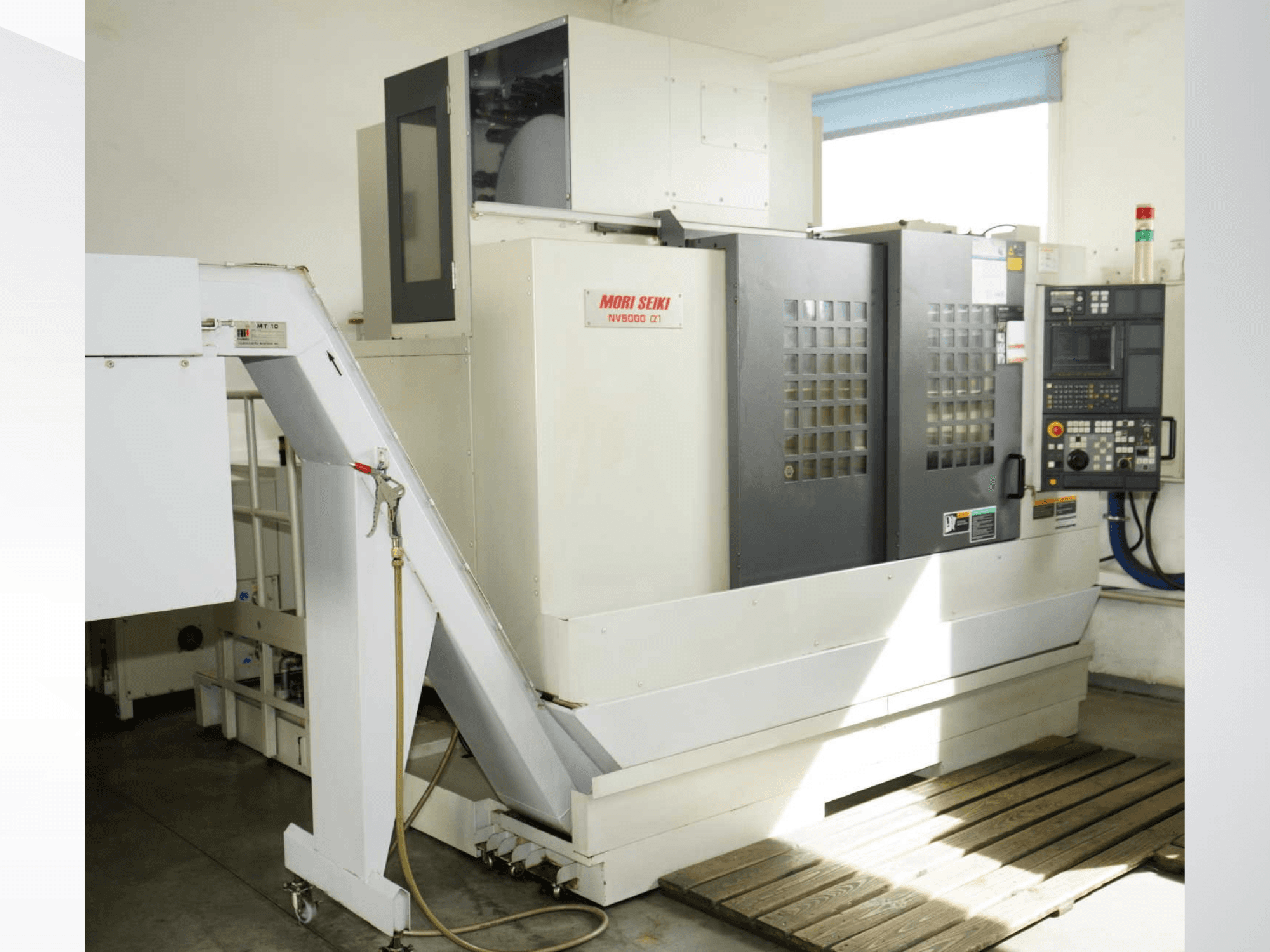 Verticaal bewerkingscentrum MORI SEIKI NV 5000 alpha1 in vooraanzicht, met het bedieningspaneel, de veiligheidsvoorzieningen en de laadruimte.