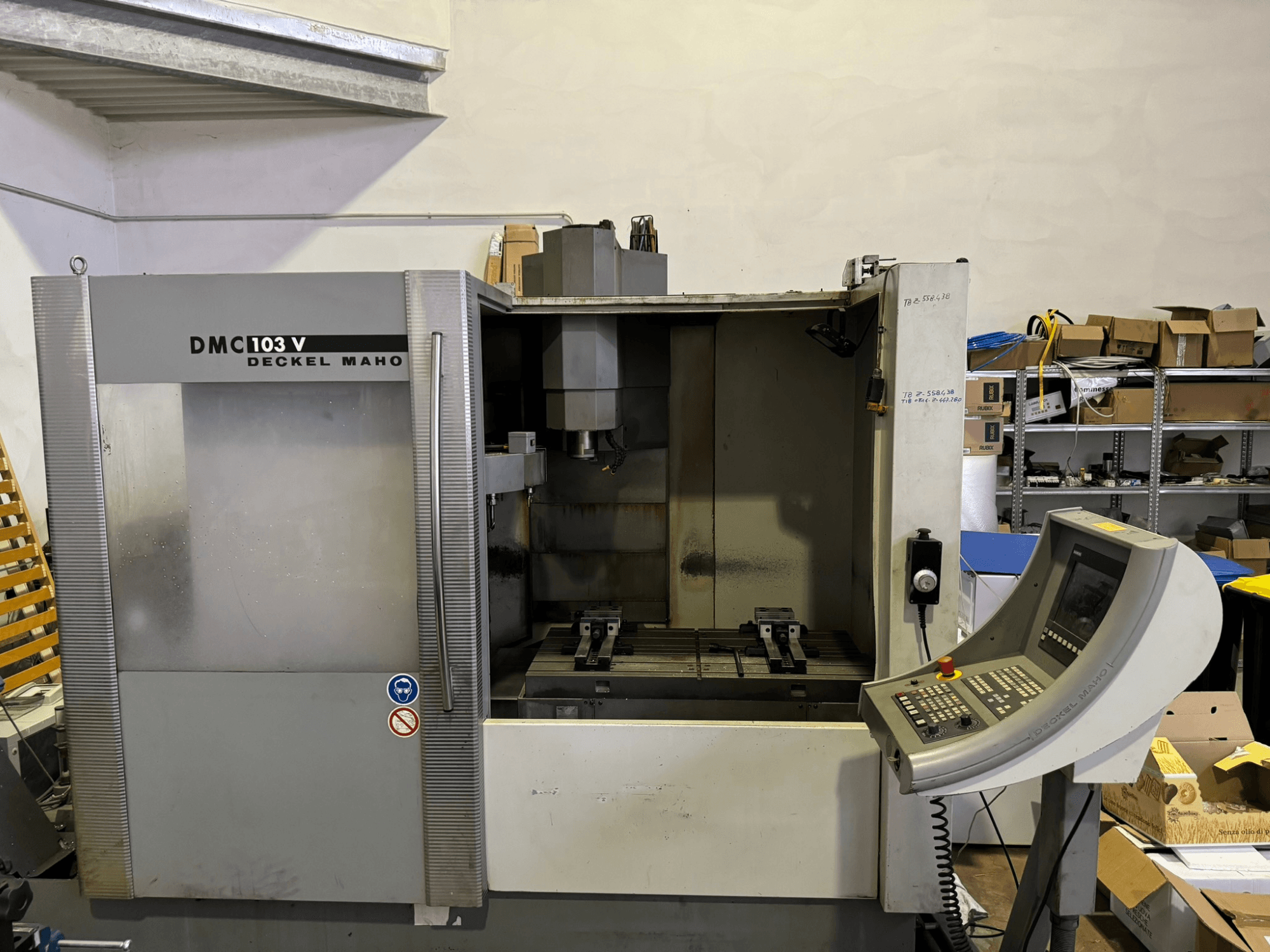 DMC 103 V Deckel Maho freesmachine, vooraanzicht, met bedieningspaneel, metalen onderdelen en opslagruimte op de achtergrond.