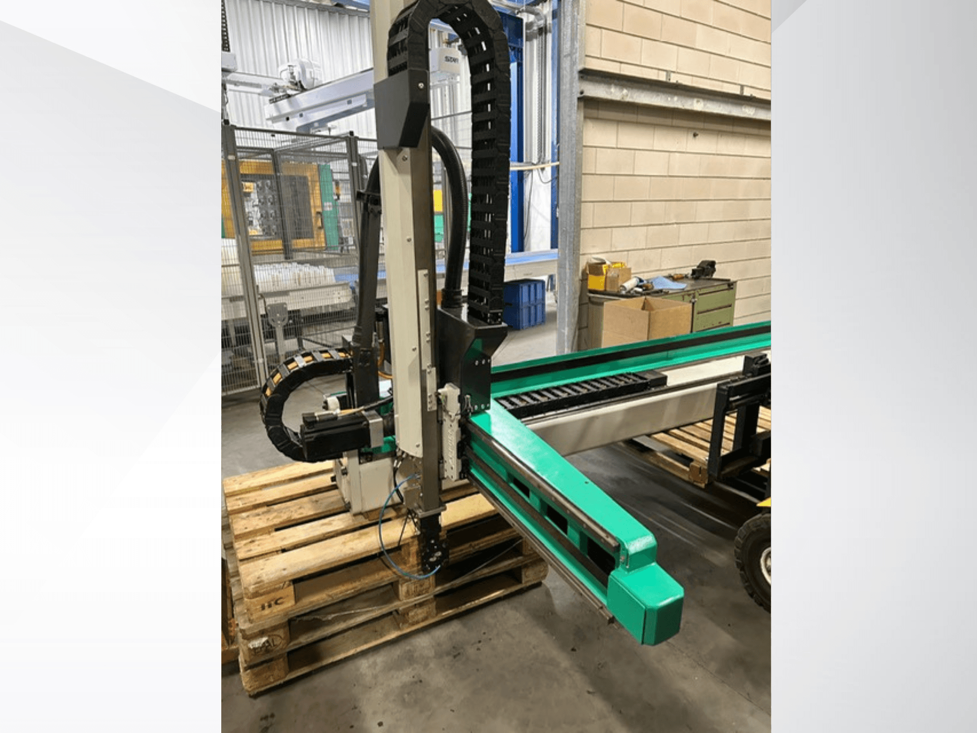 Arburg Multilift Select 15kg quer, zijaanzicht van werkstukhanteringssysteem op houten pallets, met robotarm en besturingscomponenten.
