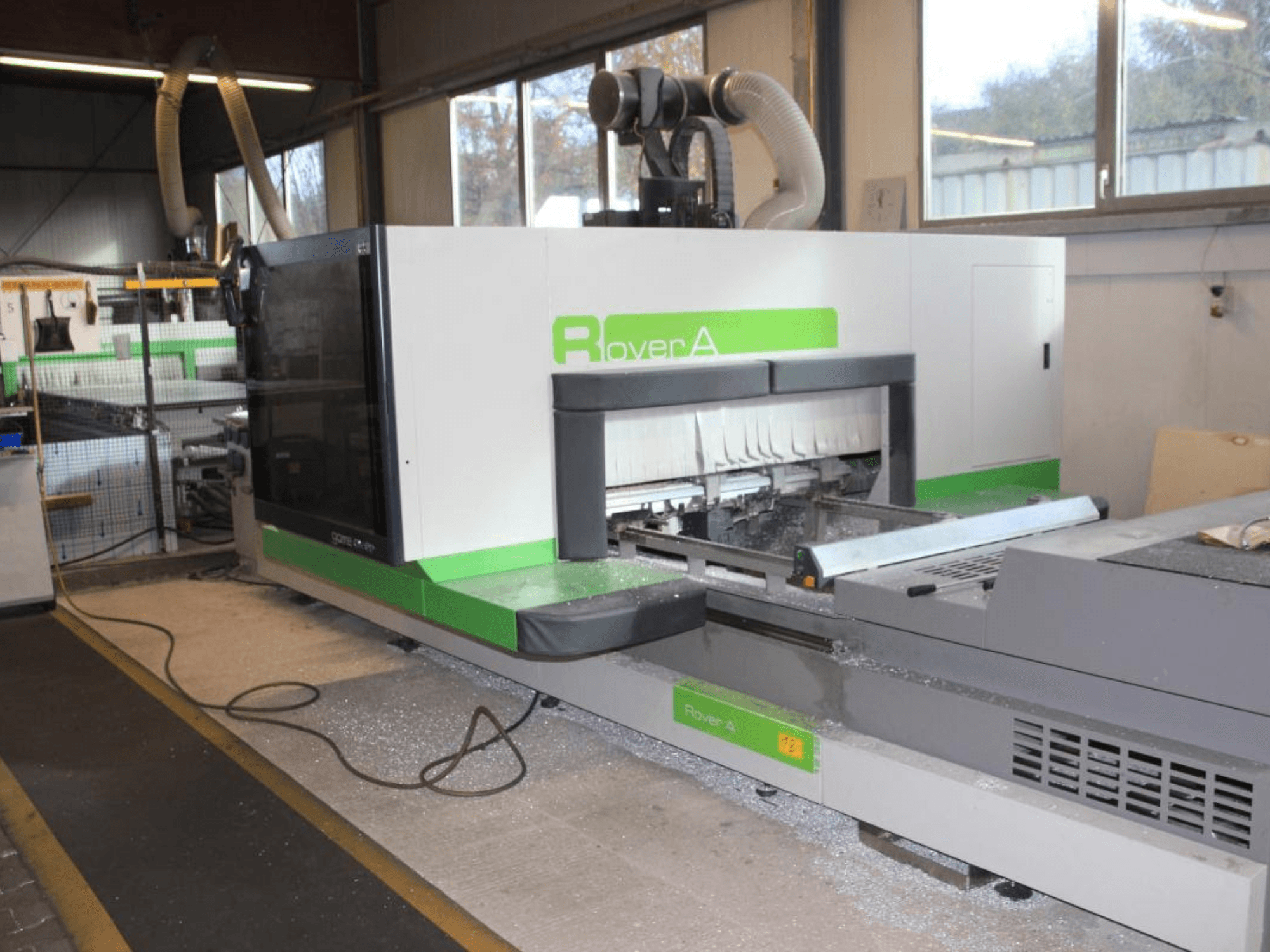BIESSE Rover A 1232 CNC bovenfrees, zijaanzicht van het freesgebied en het bedieningspaneel in een industriële omgeving.