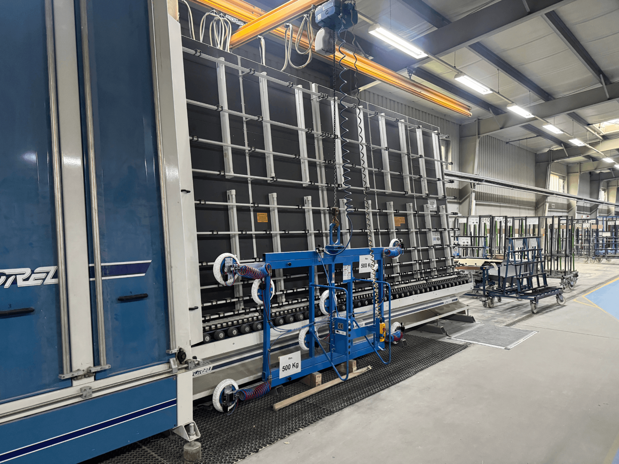 Industriële apparatuur van Drel, met een groot frame en hefmechanisme, getoond vanaf de zijkant in een fabrieksomgeving.