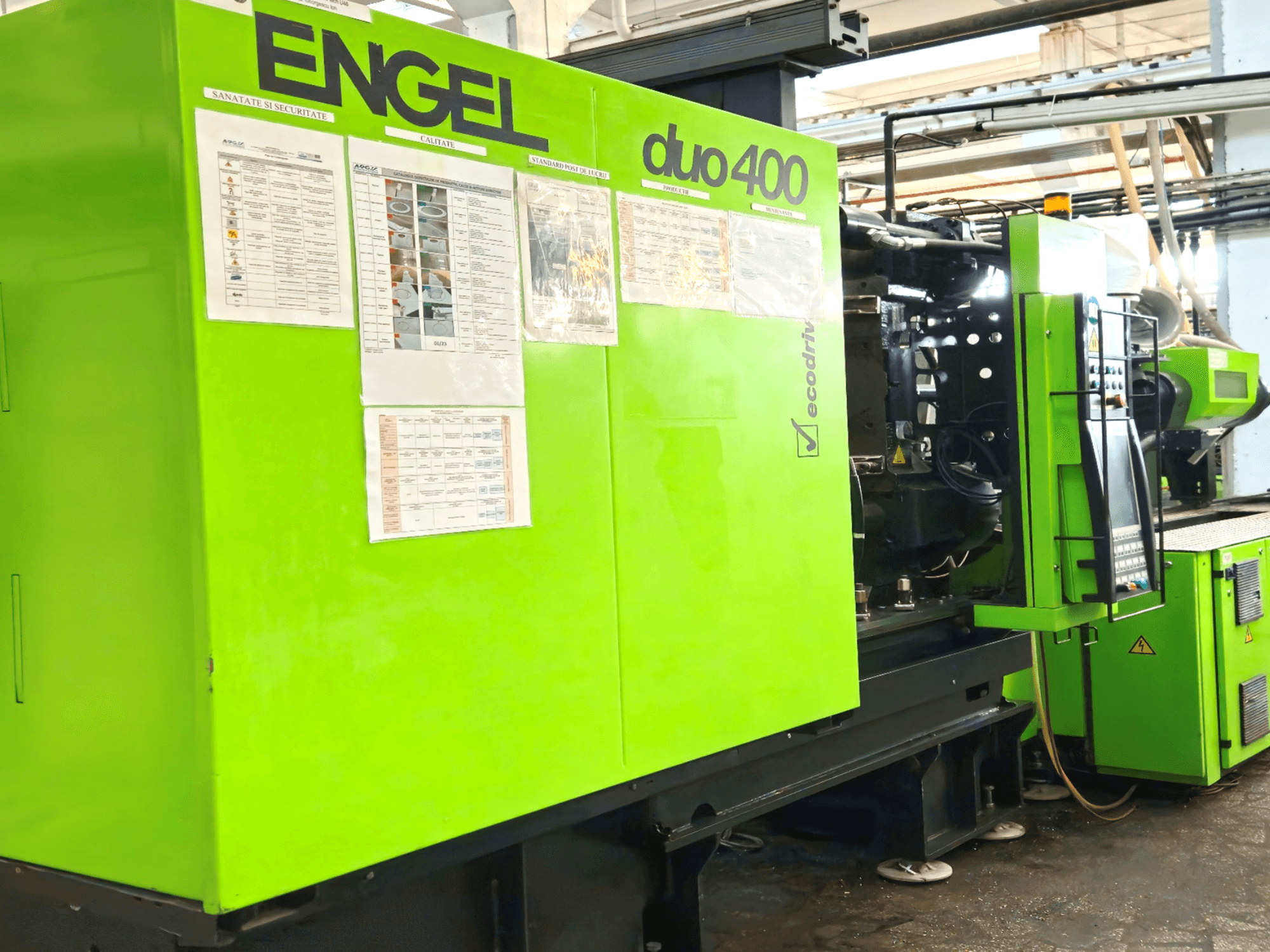 Groene ENGEL duo 400 spuitgietmachine, vooraanzicht met bedieningspaneel en veiligheidsdocumentatie aan de buitenkant.
