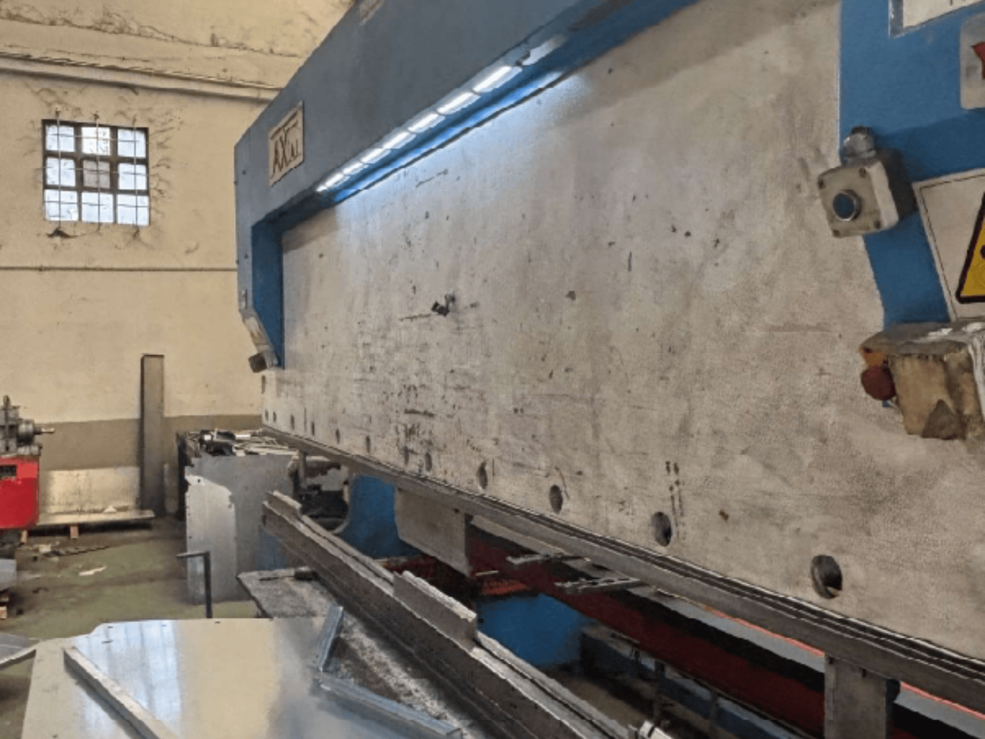 Axial PHS-W-124 pallet-handlingsysteem in een werkplaats, zijaanzicht met werkoppervlak en details van het bedieningspaneel.