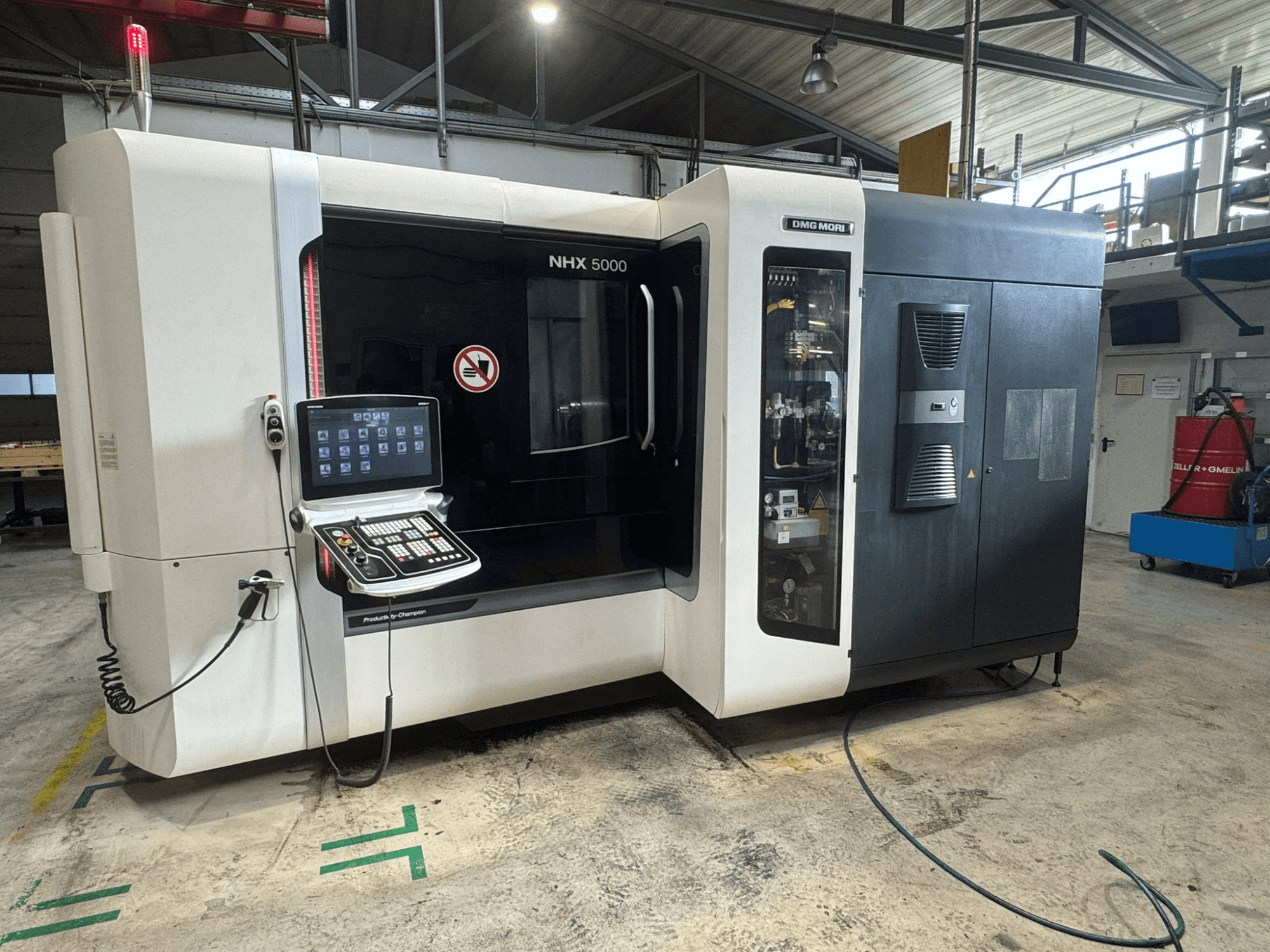 DMG MORI NHX 5000 horizontaal bewerkingscentrum, vooraanzicht met zichtbaar bedieningspaneel en veiligheidsindicatoren.