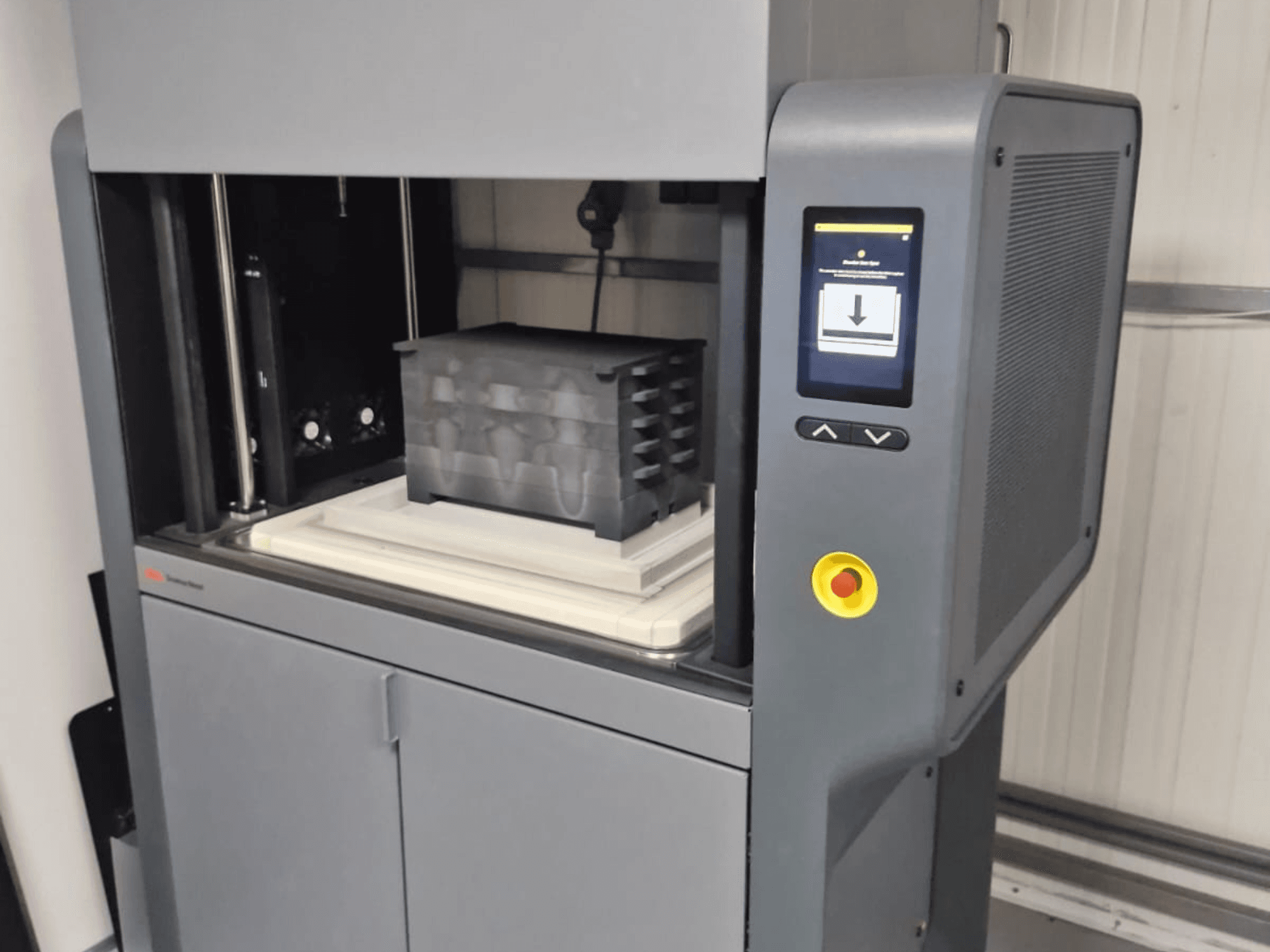 Metal Studio 2 3D printer van Desktop Metal, vooraanzicht met bedieningspaneel en printbed met zwarte container.