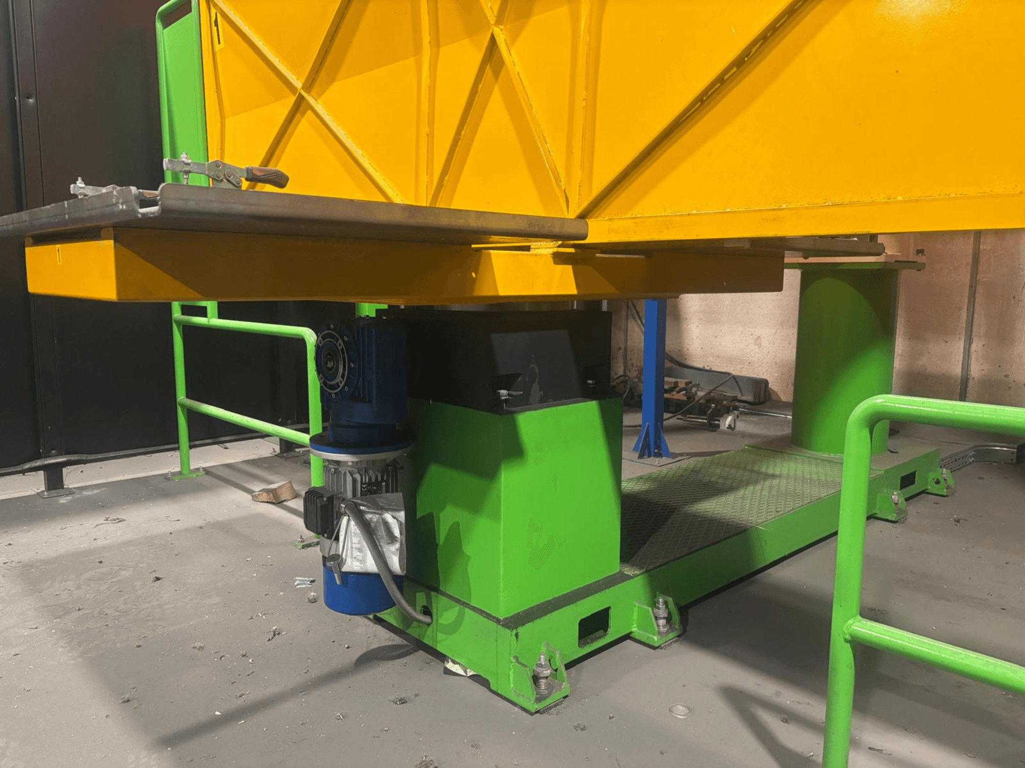 Groen met gele industriële machines vanuit een laag vooraanzicht, met een motor en een platform met een gestructureerd oppervlak.