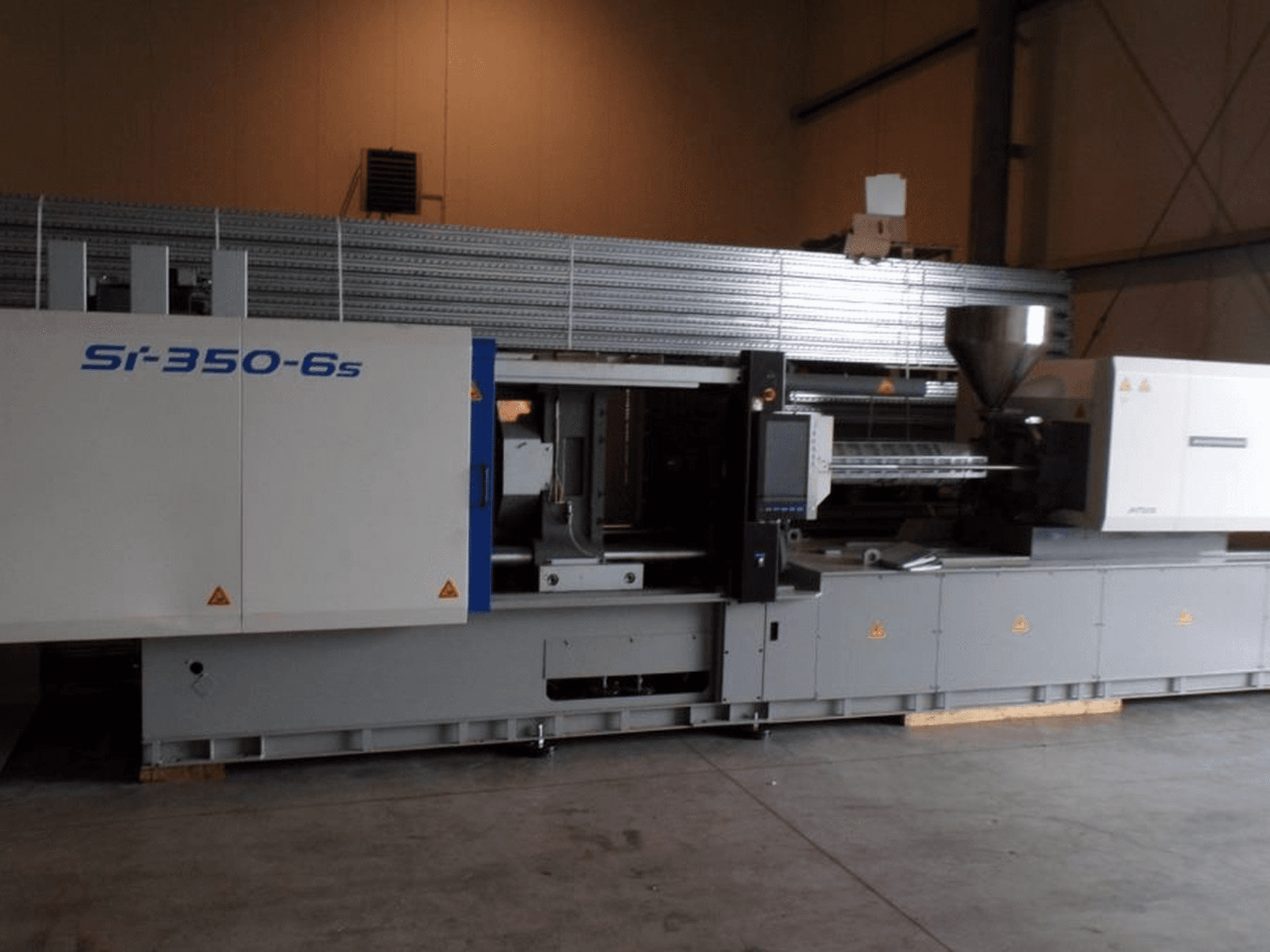 Si-350-6s spuitgietmachine in zijaanzicht, met een trechter en bedieningspaneel, in een ruime industriële omgeving.