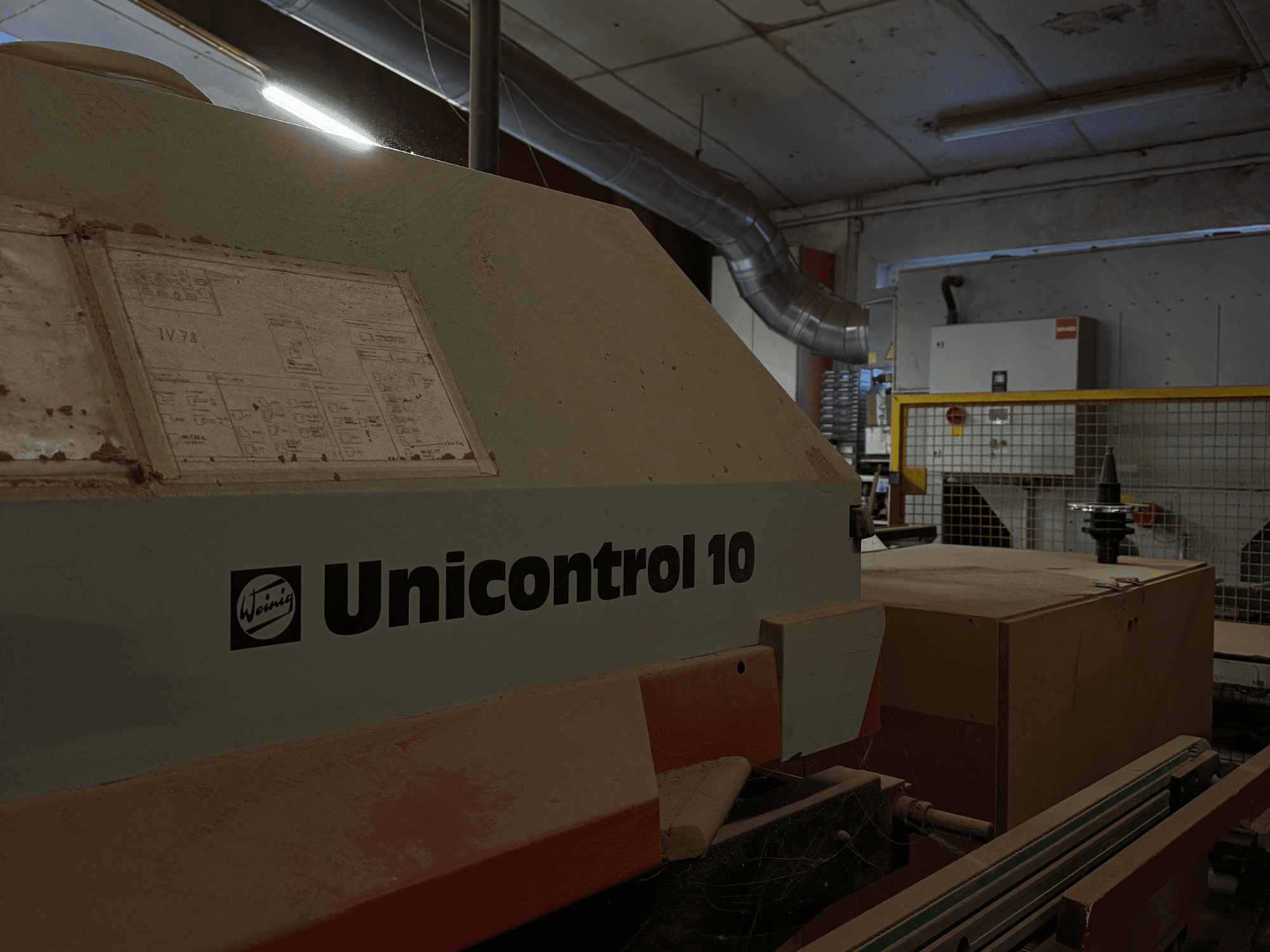 Weinig Unicontrol 10 machine gezien vanaf de zijkant, stoffig oppervlak, technische schema's zichtbaar op het voorpaneel.