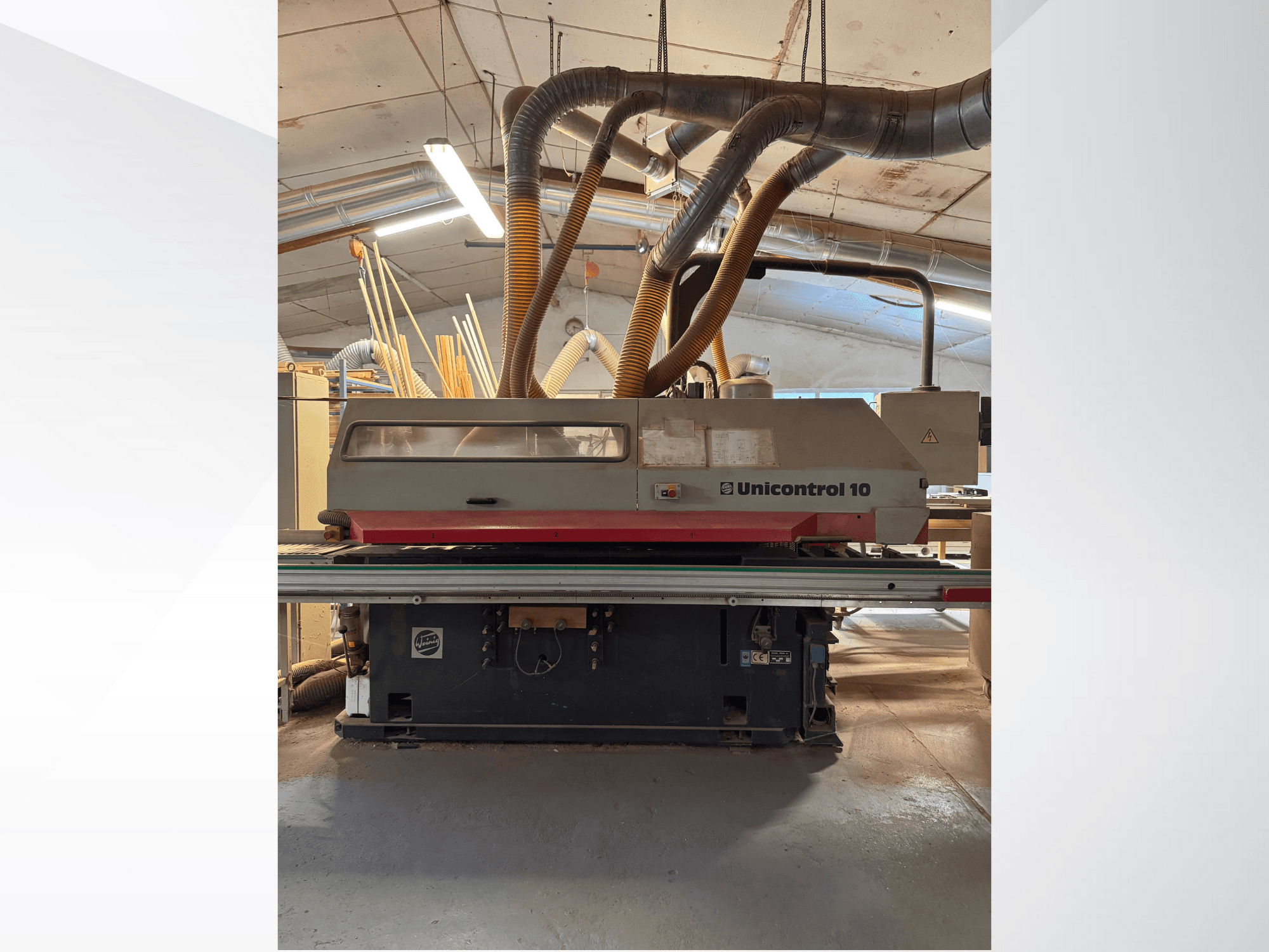 Vooraanzicht van een Unicontrol 10 houtbewerkingsmachine, met stofafzuigbuizen en bedieningselementen.