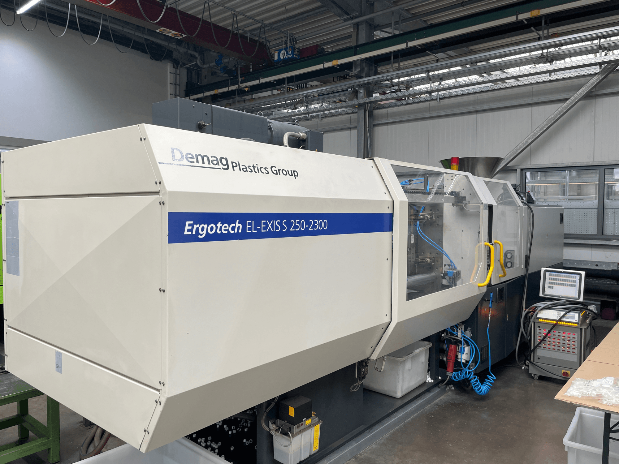 Demag Ergotech EL-EXIS S 250-2300 spuitgietmachine, zijaanzicht, met het bedieningspaneel en het toevoersysteem.