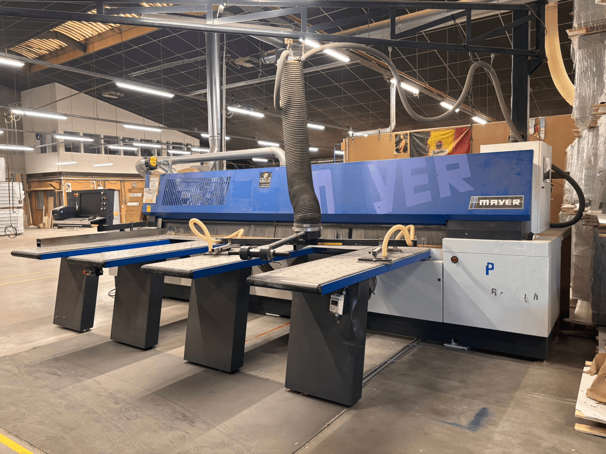 Mayer CNC machine met blauwe panelen, vooraanzicht; heeft meerdere werktafels en een stofafzuigsysteem voor houtbewerking.