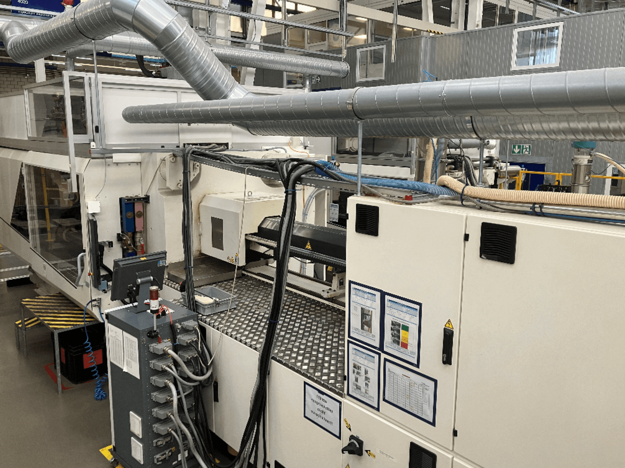 Industriële machines met uitgebreide leidingen, bedieningspanelen en bedieningshandleidingen, bekeken vanuit een top-down perspectief.