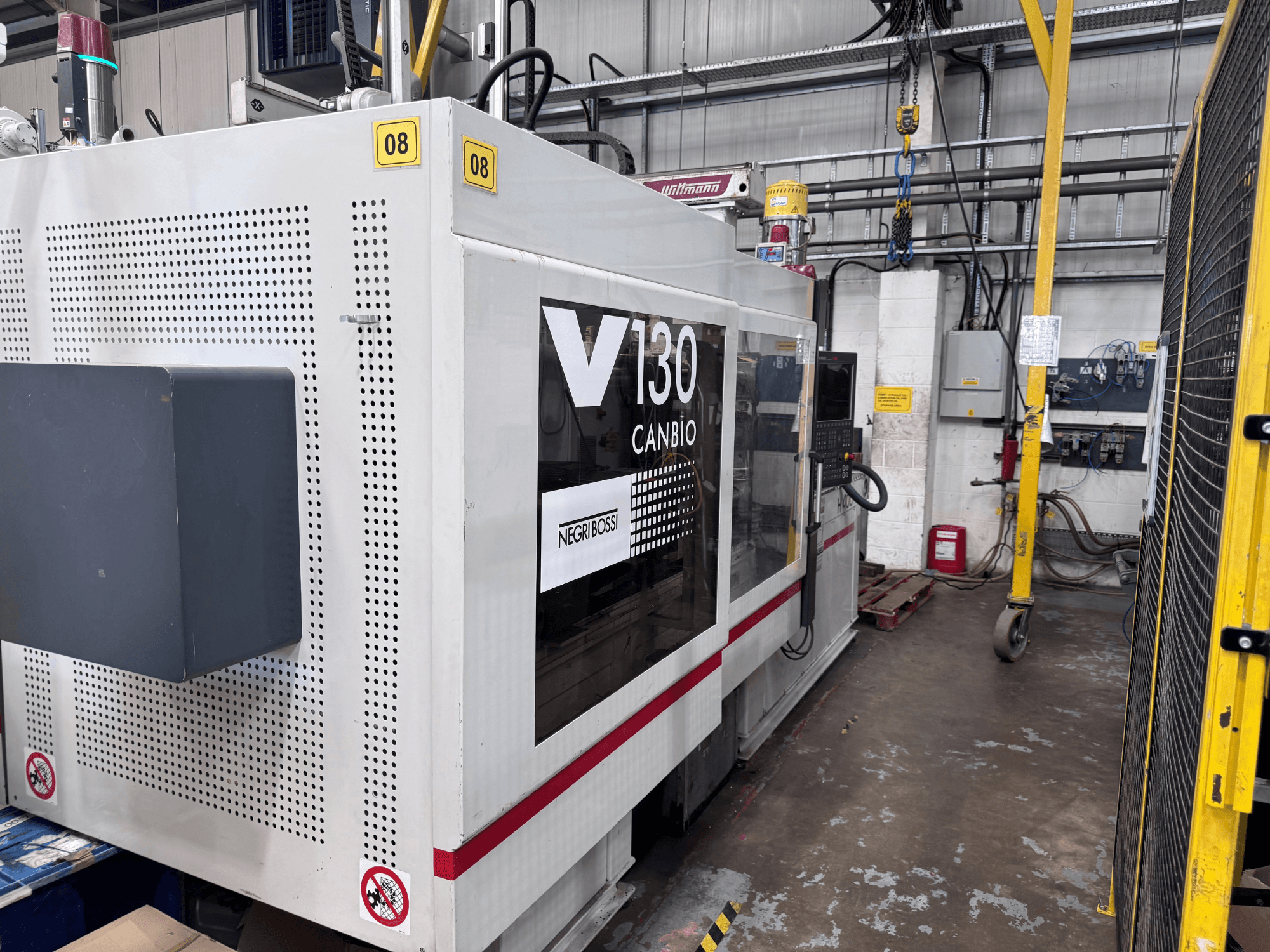 Negri Bossi 1300H-400 hydraulische spuitgietmachine, zijaanzicht, met bedieningspaneel en veiligheidsborden.
