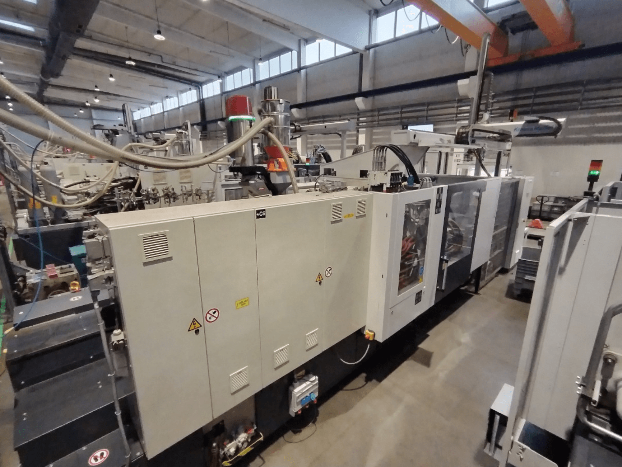 Industriële spuitgietmachine in zijaanzicht, met bedieningspaneel en veiligheidswaarschuwingen. Merk: Onbekend.