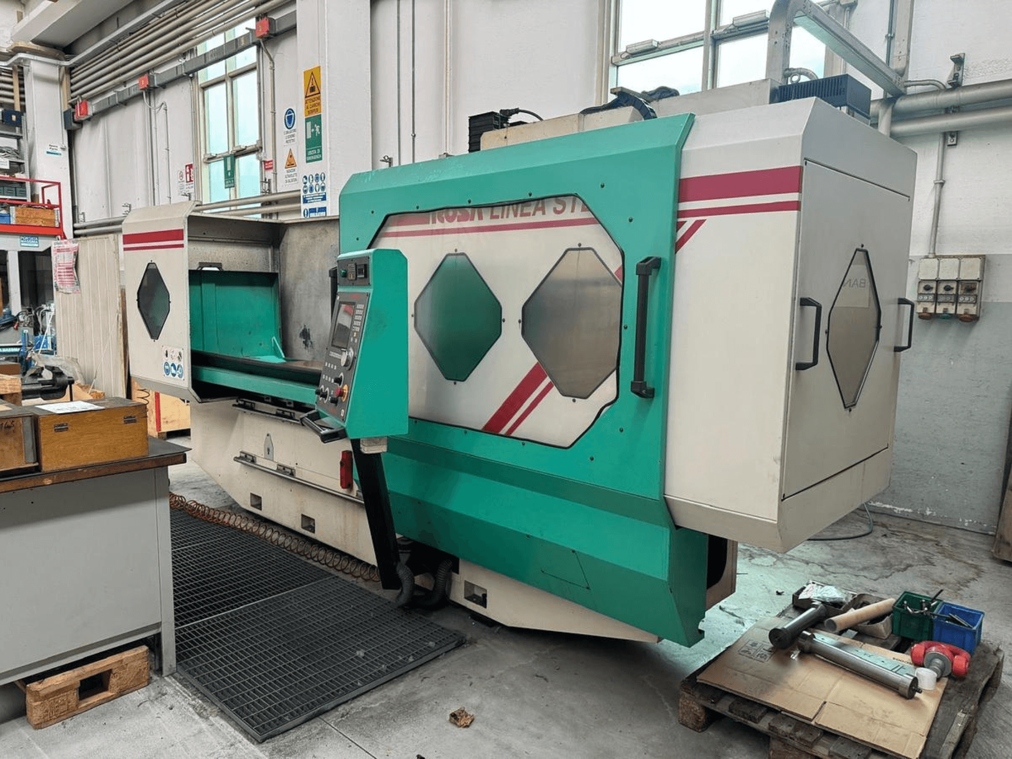 Groen-witte precisiemachine, vooraanzicht, met bedieningspaneel, werkgebied en gereedschap op een pallet. Merk: BAMB.