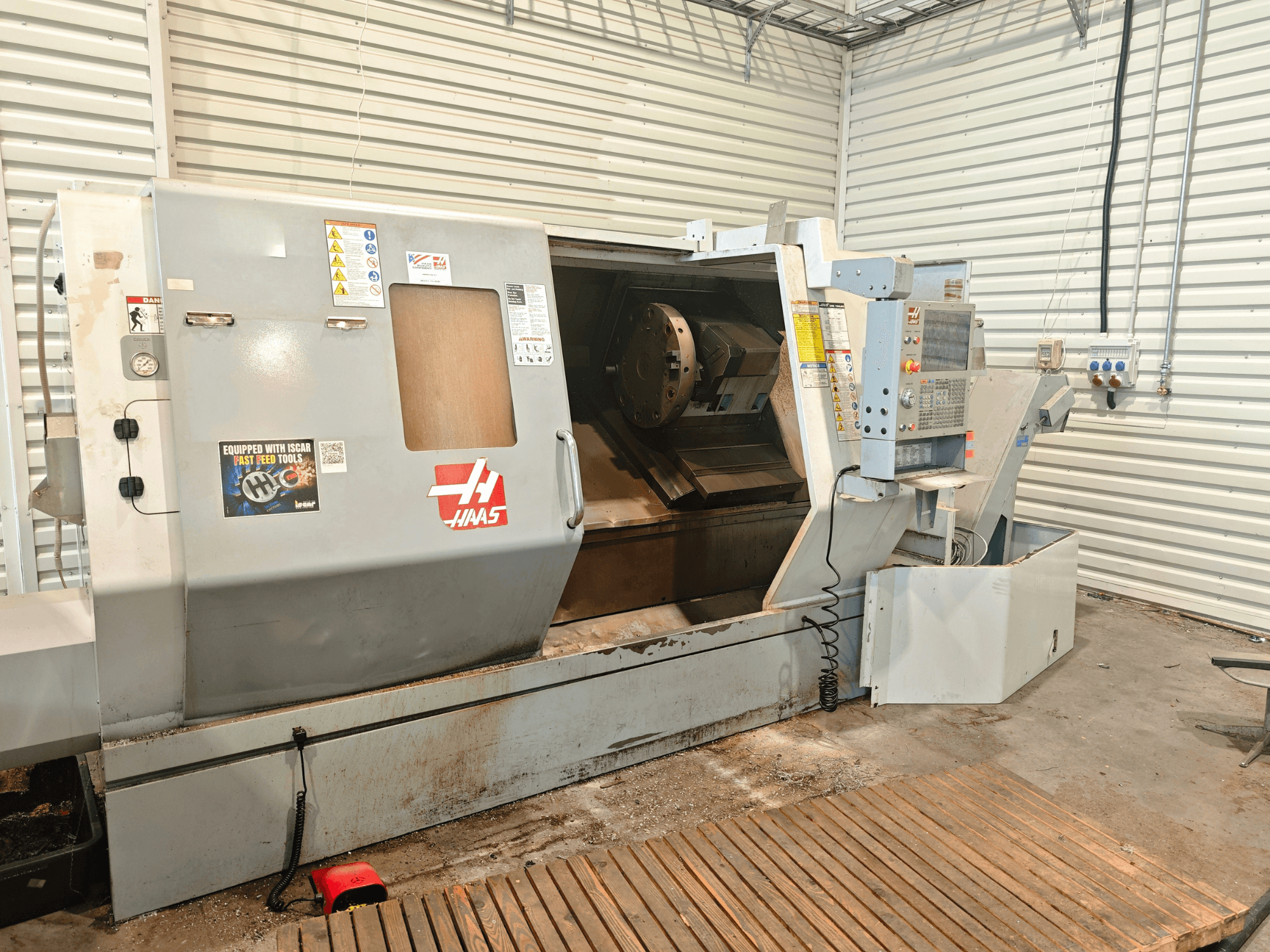Haas SL-40HE horizontale draaibank, vooraanzicht, met daarop het bedieningspaneel, het werkgebied en de veiligheidslabels.