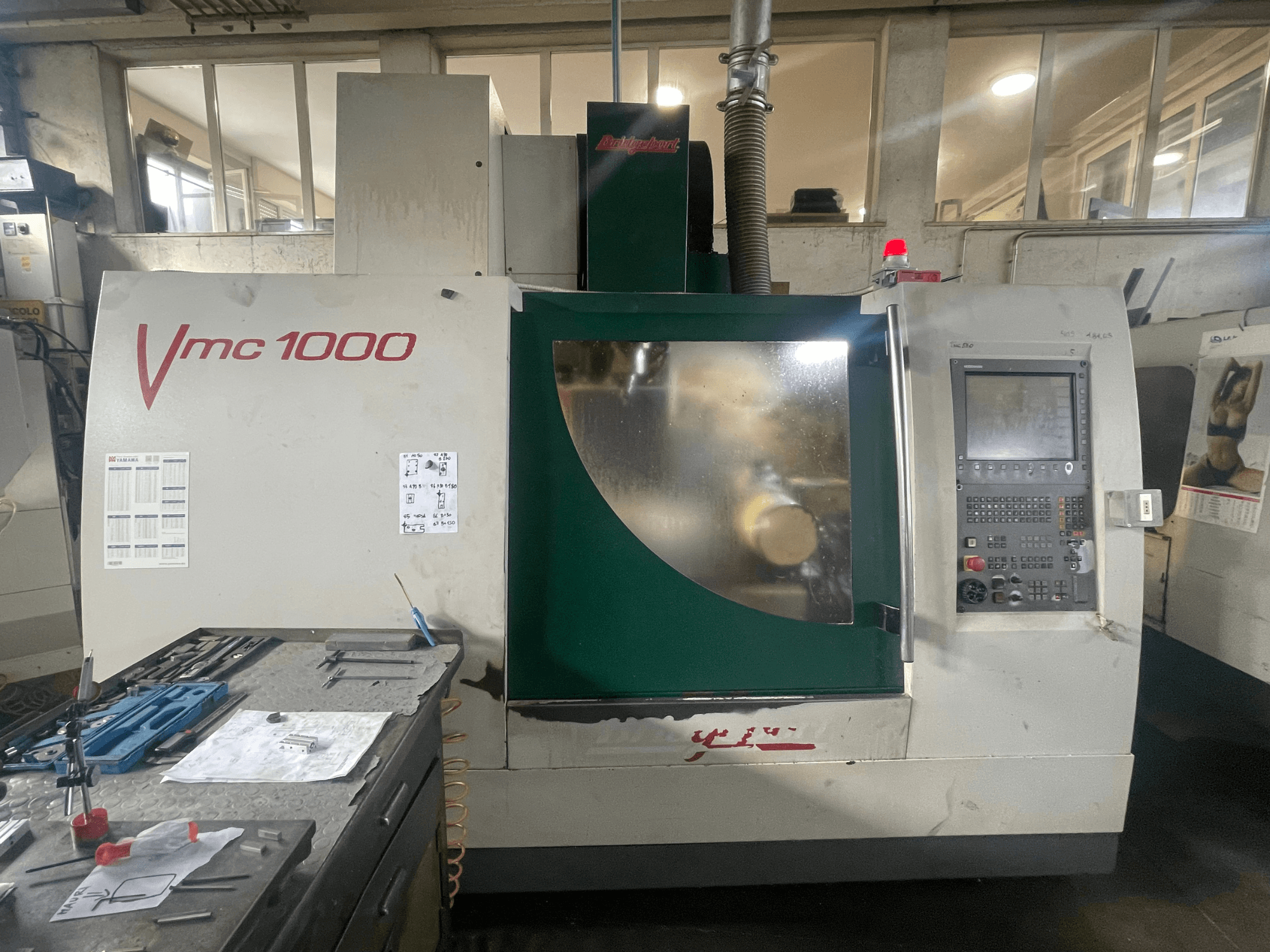 Verticaal bewerkingscentrum Bridgeport VMC 1000/30, vooraanzicht, met weergave van het bedieningspaneel en de hoofdbehuizing, met gereedschappen ernaast.