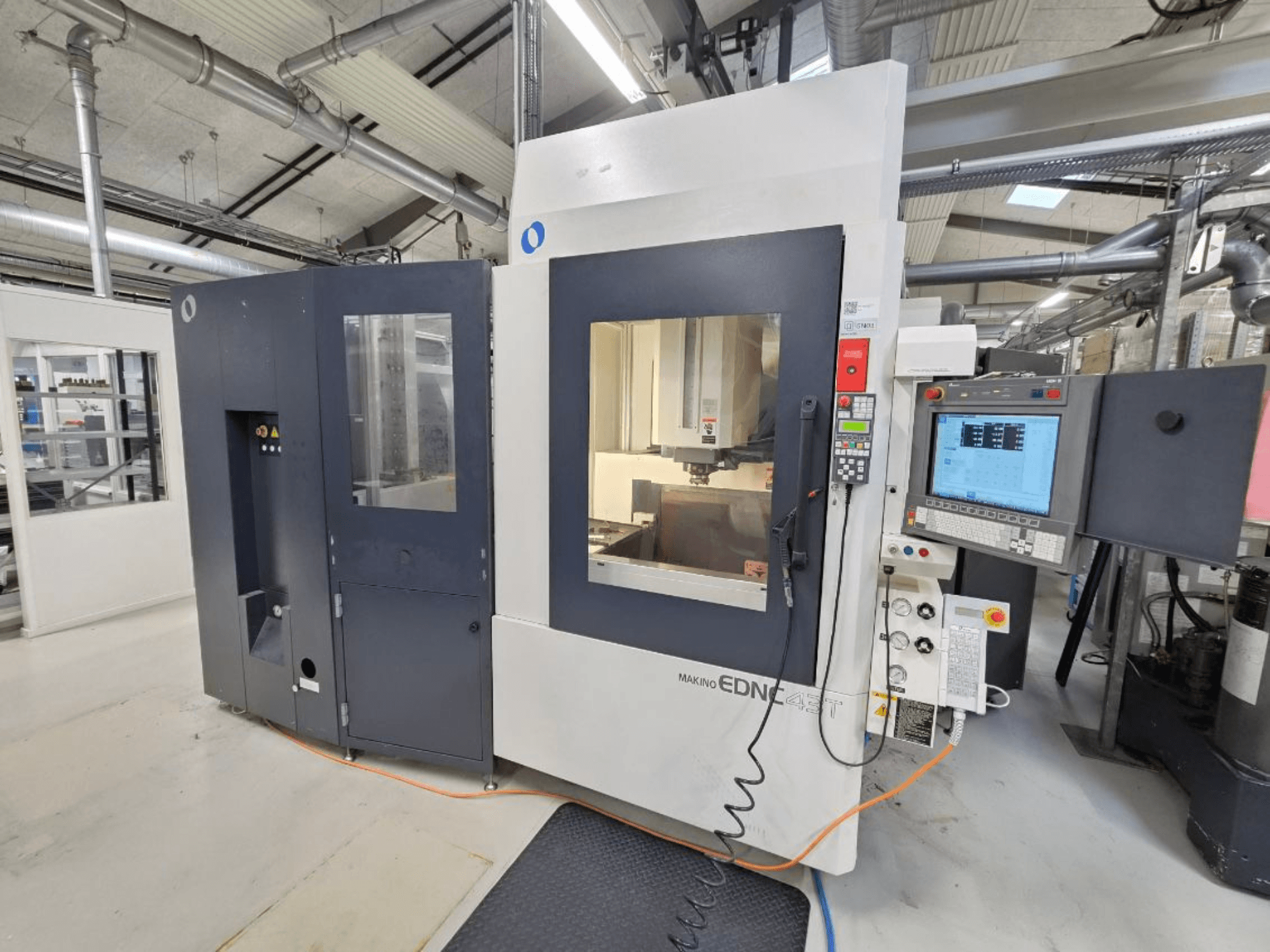 Vooraanzicht van een Makino EDNC 43T zinkvonkmachine, met Erowa-robot, bedieningselementen en zichtbaar werkgebied.
