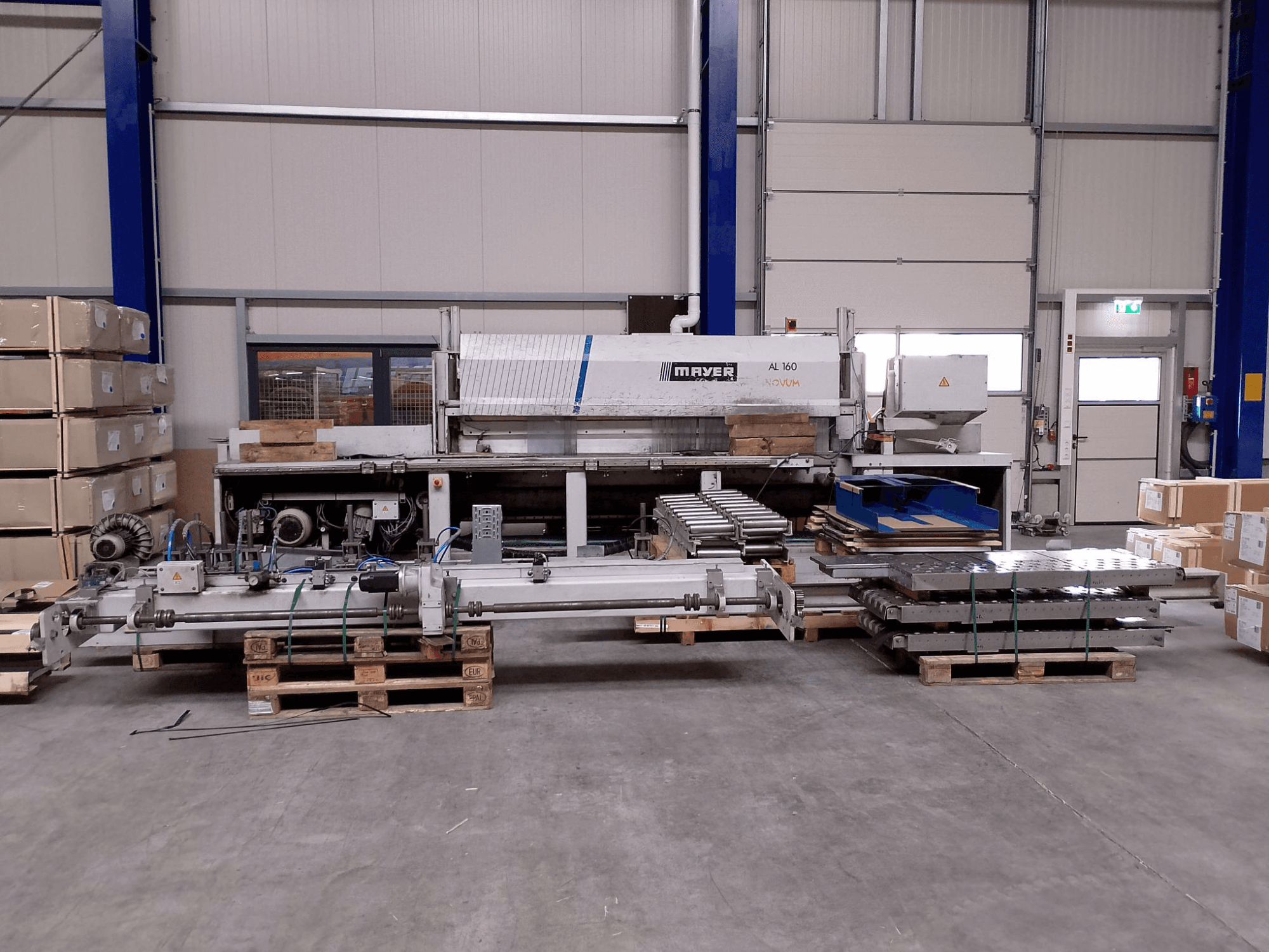 MAYER AL160 paneelzaag in een magazijn met pallets, met de zaagtafel en machineonderdelen, vooraanzicht.