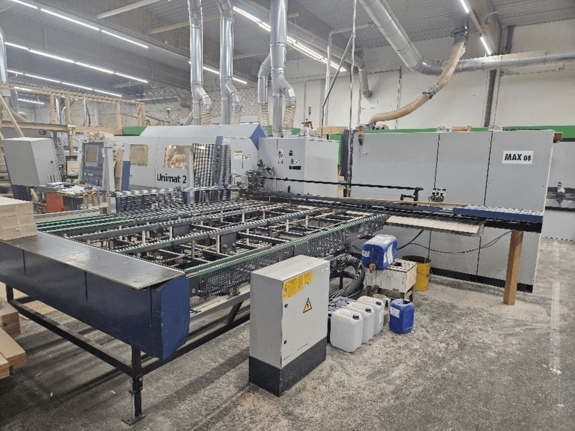 Zijaanzicht van een Unimat 2 CNC machine in een werkplaats, met transportbanden en technische componenten met zichtbare Max 08 unit.