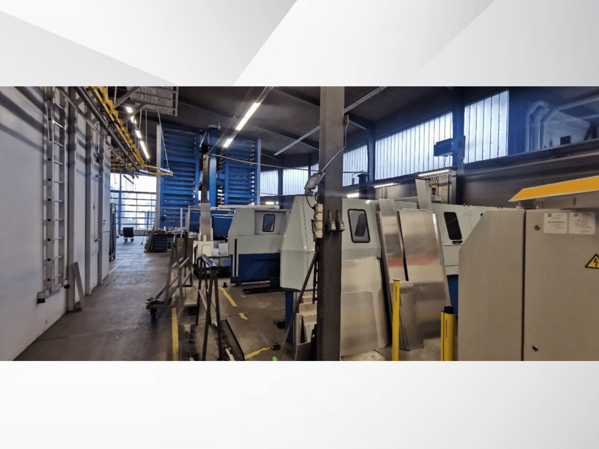 Industriële werkplaatsscène met verschillende machines en apparatuur in zijaanzicht, met metalen oppervlakken en zichtbare veiligheidsvoorzieningen.
