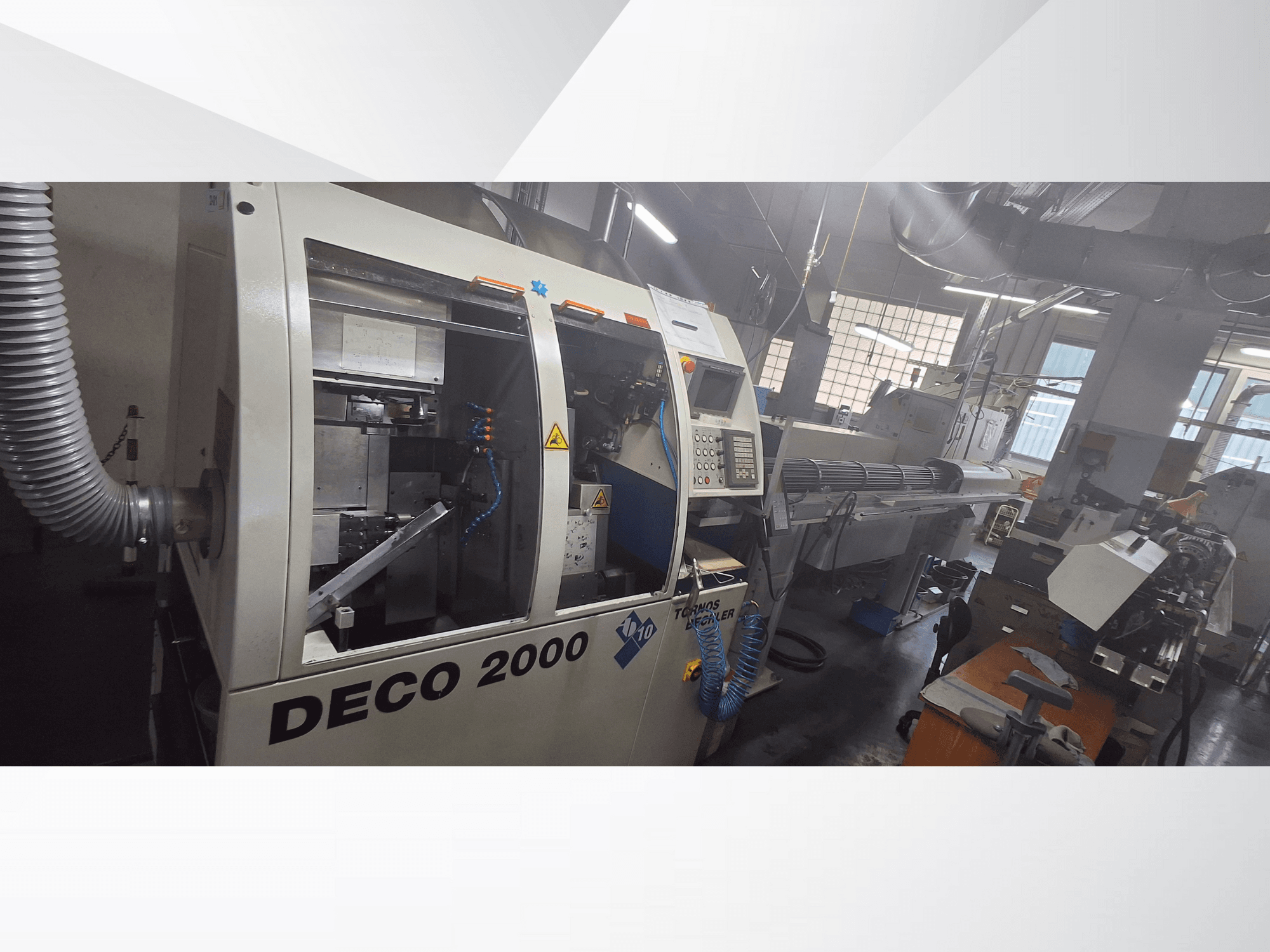 DECO 2000 CNC machine in een werkplaats, vooraanzicht, met rechts de bedieningselementen en een lange werkstukopstelling.