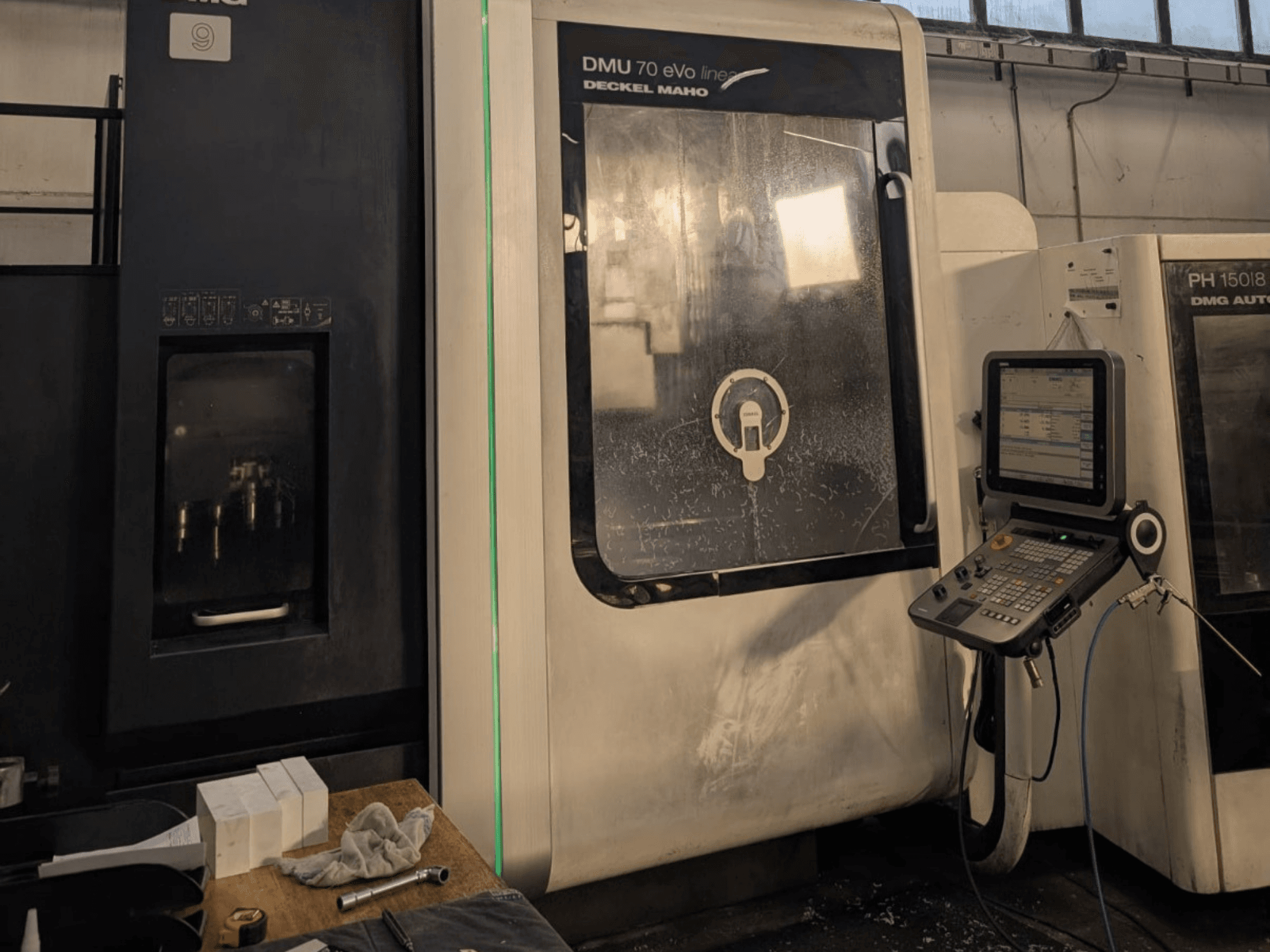 DMG DECKEL MAHO DMU 70 EVO Lineair verticaal bewerkingscentrum, vooraanzicht met bedieningspaneel, gereedschappen en werkruimte zichtbaar.