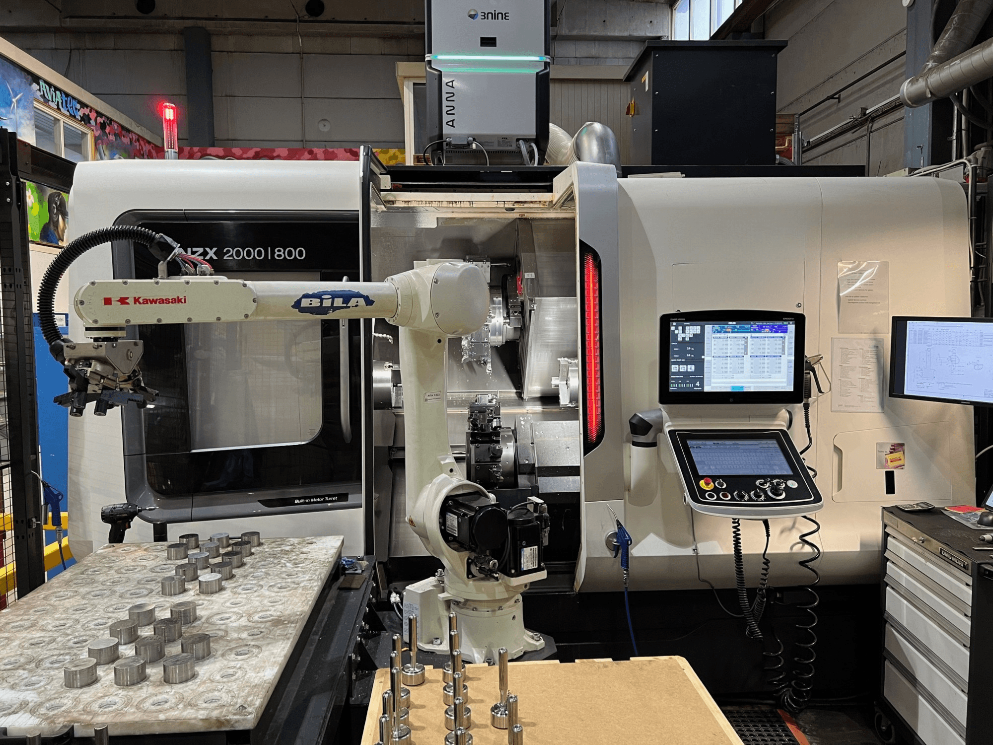 Horizontale draaibank DMG MORI NZX 2000/800SY in een werkplaats, met zichtbare Kawasaki-robotarm en bedieningselementen.