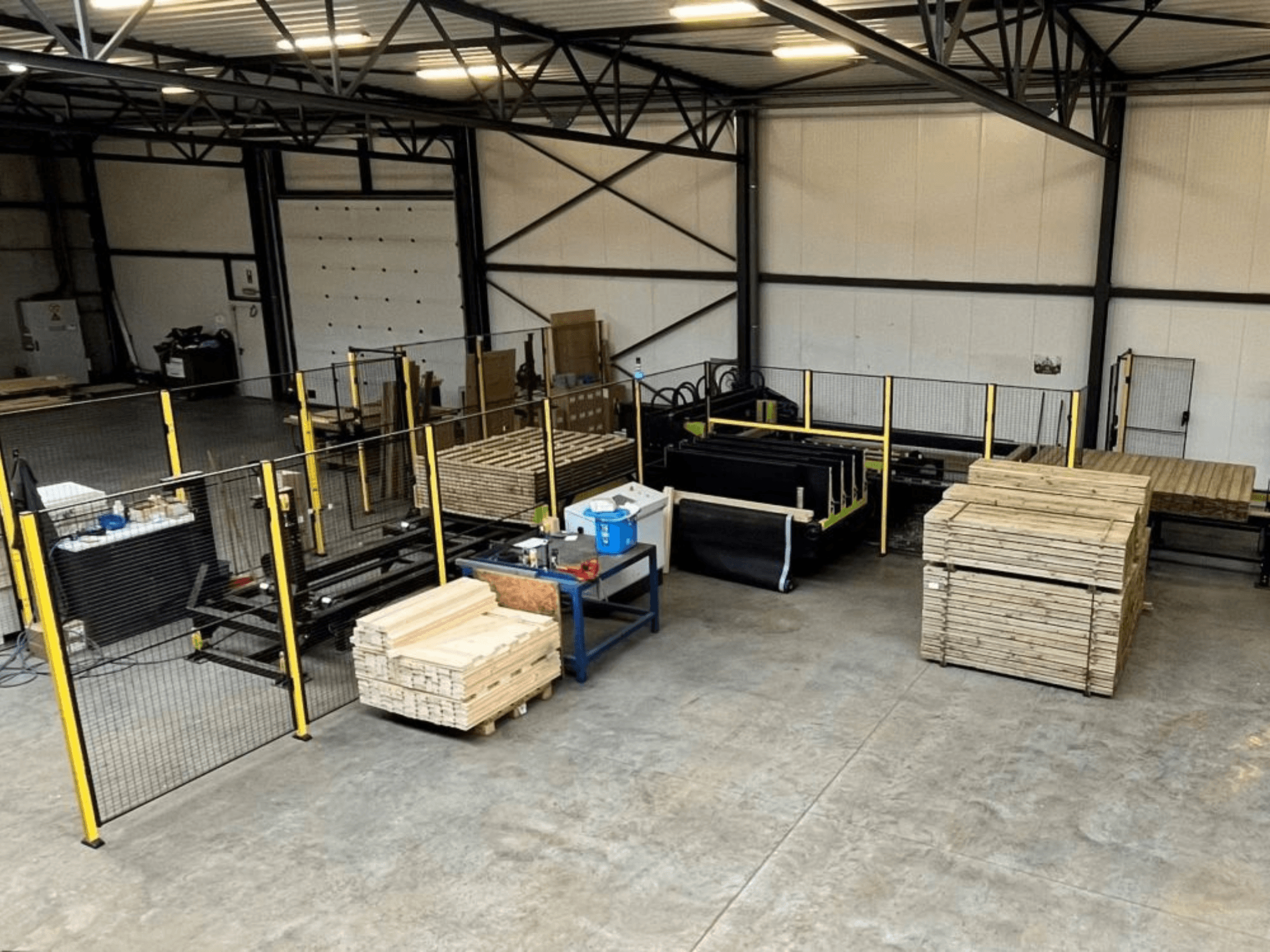 Complete productielijn (ISM ATM-01) voor hout, van bovenaf gezien, met machines, houten pallets en veiligheidshekken.
