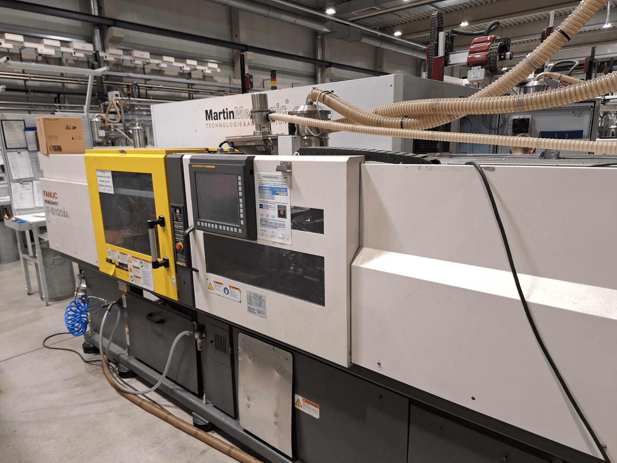 FANUC Roboshot S100iA elektrische spuitgietmachine, zijaanzicht, uitgerust met touchscreen en veiligheidslabels.