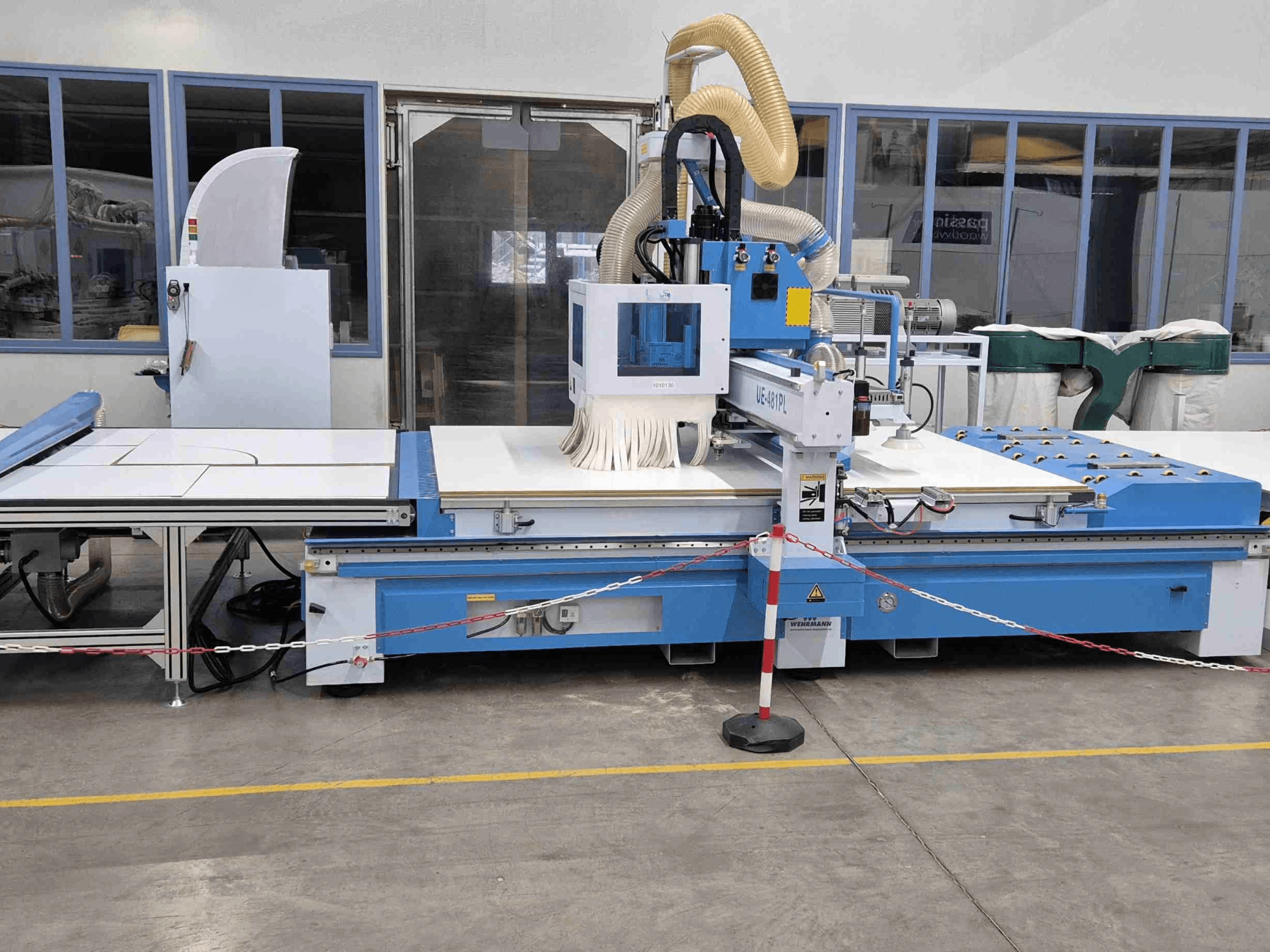 Blauwe CNC bovenfrees UE-621PL van de voorkant, met een grote snijtafel en een aangesloten stofafzuigsysteem.