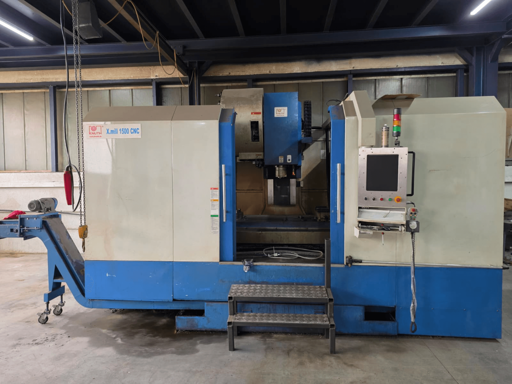 KNUTH X-MILL 1500 CNC-verticaal bewerkingscentrum, zijaanzicht, met bedieningspaneel, treden en afvoerband.
