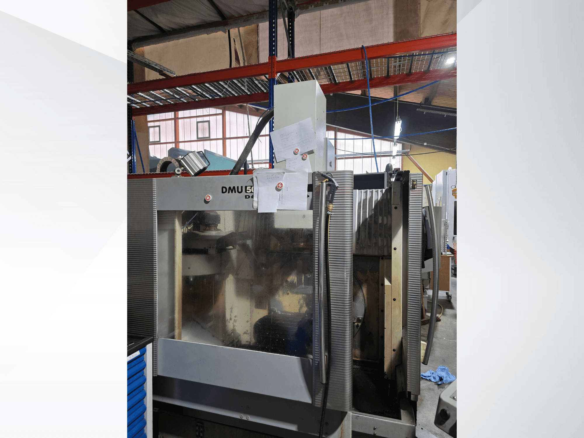 DMU 50 3-assig CNC-bewerkingscentrum in een werkplaats, van voren gezien, met operationele componenten en bijgevoegde documenten.